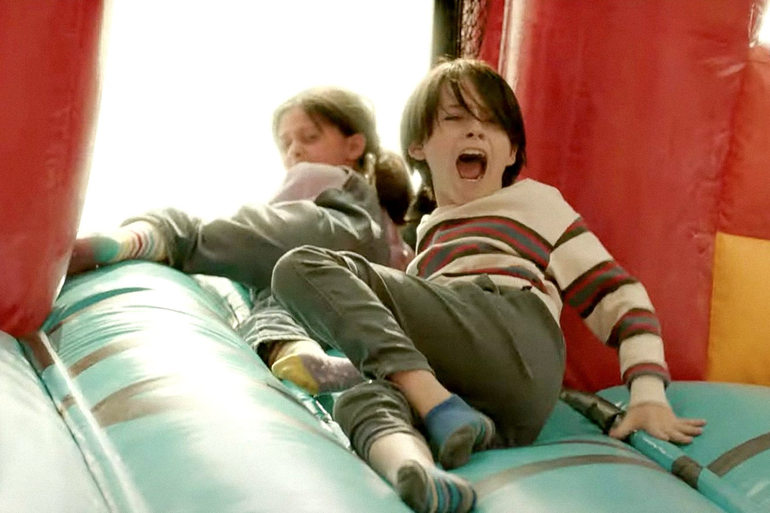 Children screaming and clinging to a bounce house.