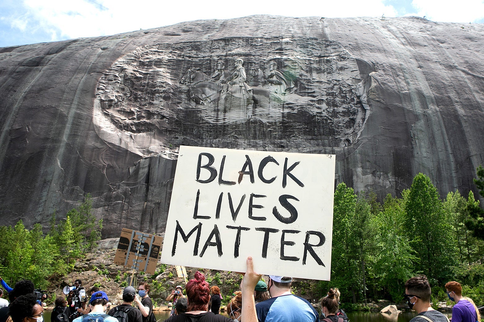 Someone holds up a sign that says Black Lives Matter in front of the massive bas-relief on Stone Mountain.