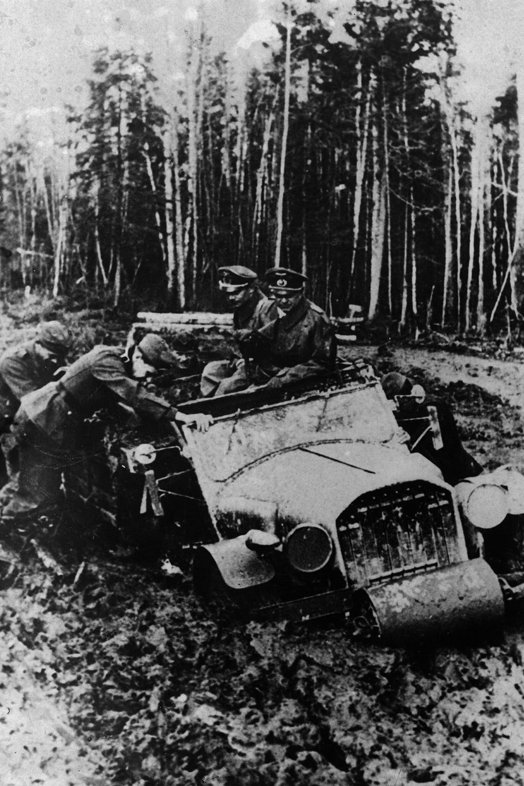 Men try to get an automobile out of mud.