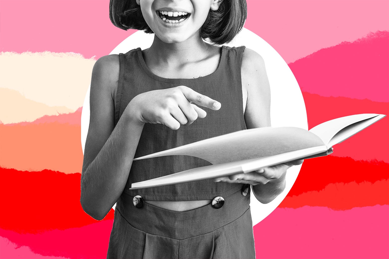 Young girl holding a book, pointing and laughing.