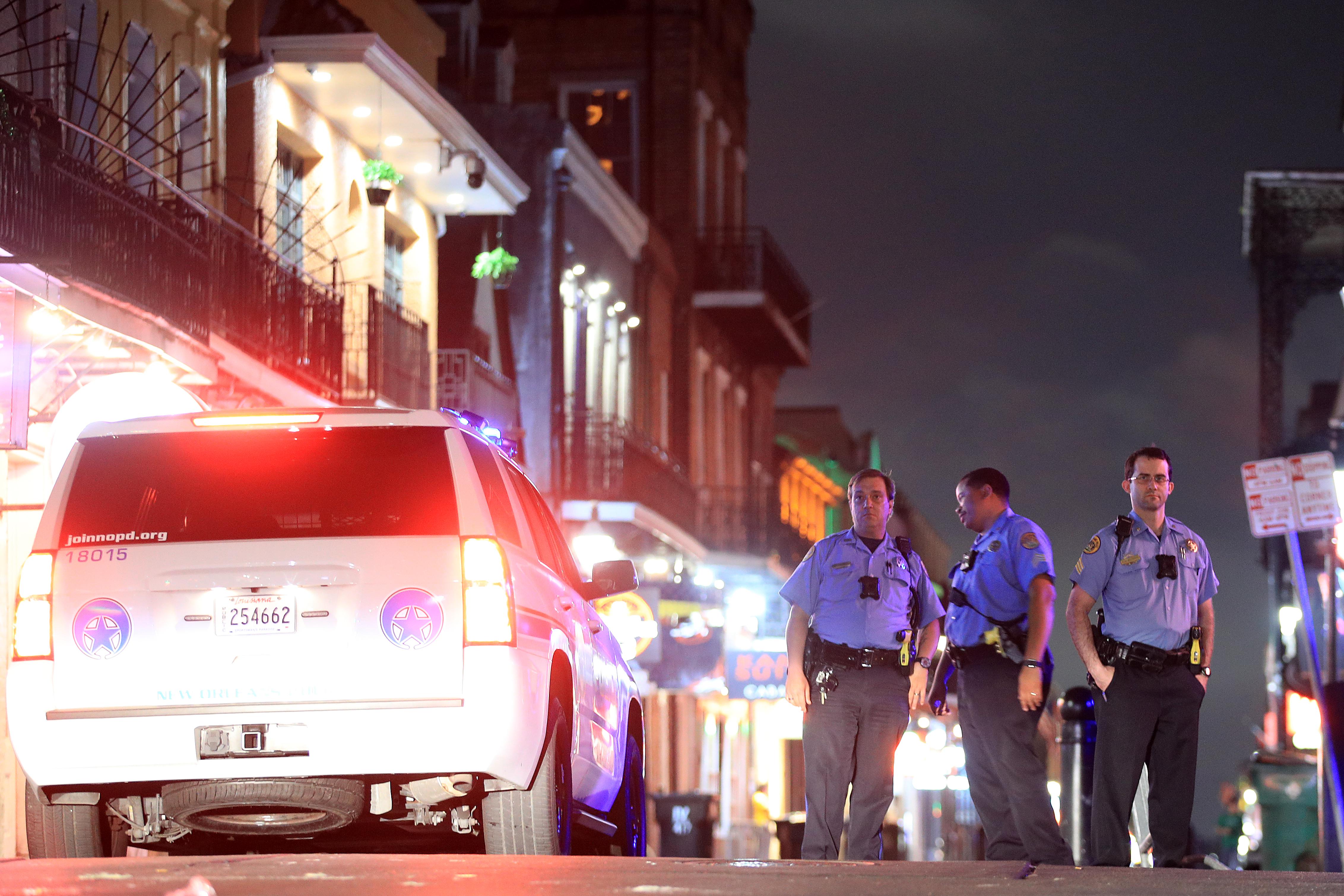 Police officers stand next to a police SUV on Bourbon Street