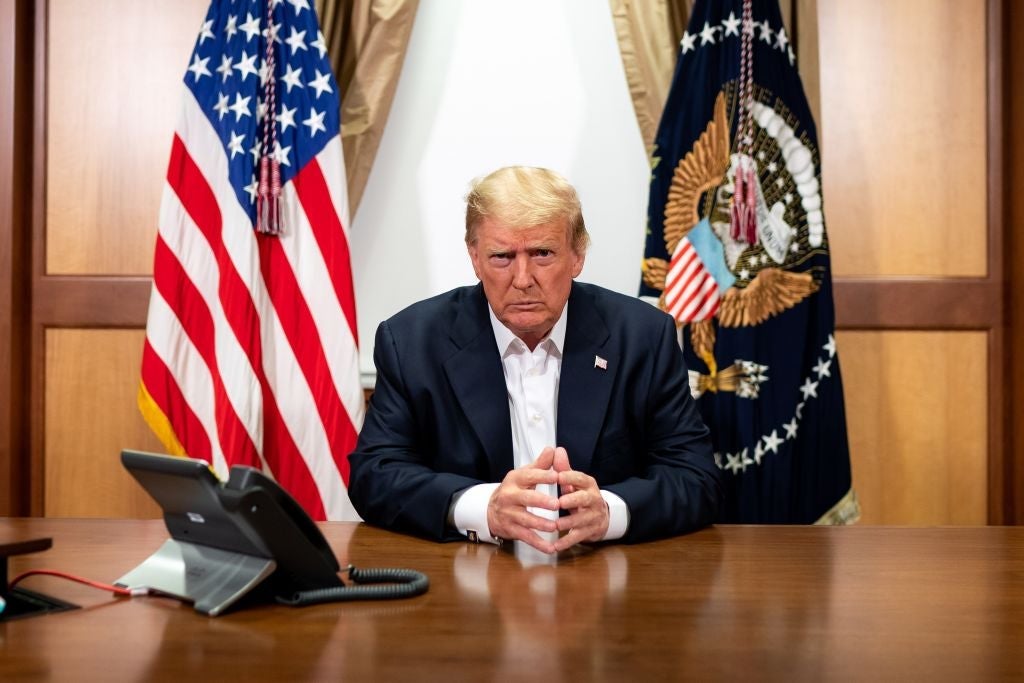 Trump, seated at a conference room table inside the Walter Reed Medical Center, looks into the camera.