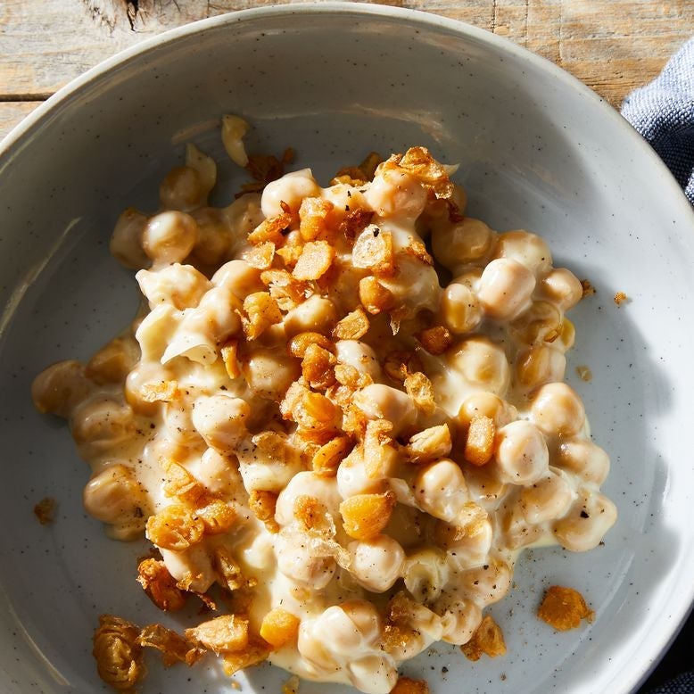 A bowl of chickpeas in cheddar sauce with chopped chickpea crispies on top