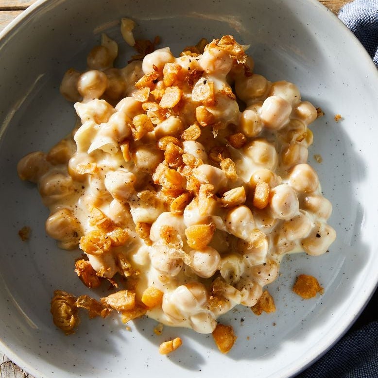 A bowl of chickpeas in cheddar sauce with chopped chickpea crispies on top
