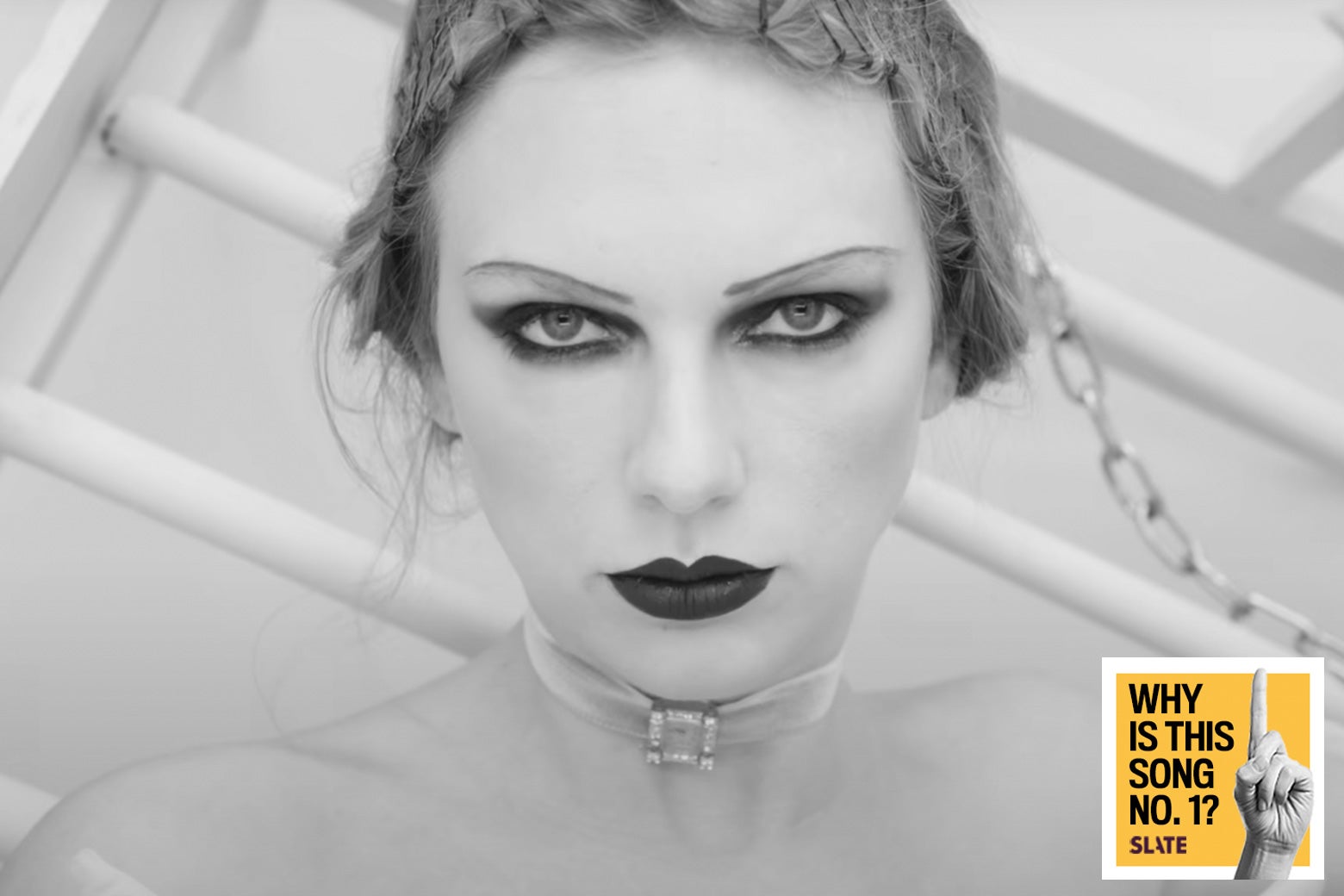 Taylor Swift looks directly at the camera and is wearing lots of black eyeshadow and black lipstick in a black-and-white photo. In the bottom, a bright yellow logo reads "Why Is This Song No. 1?" and is branded Slate