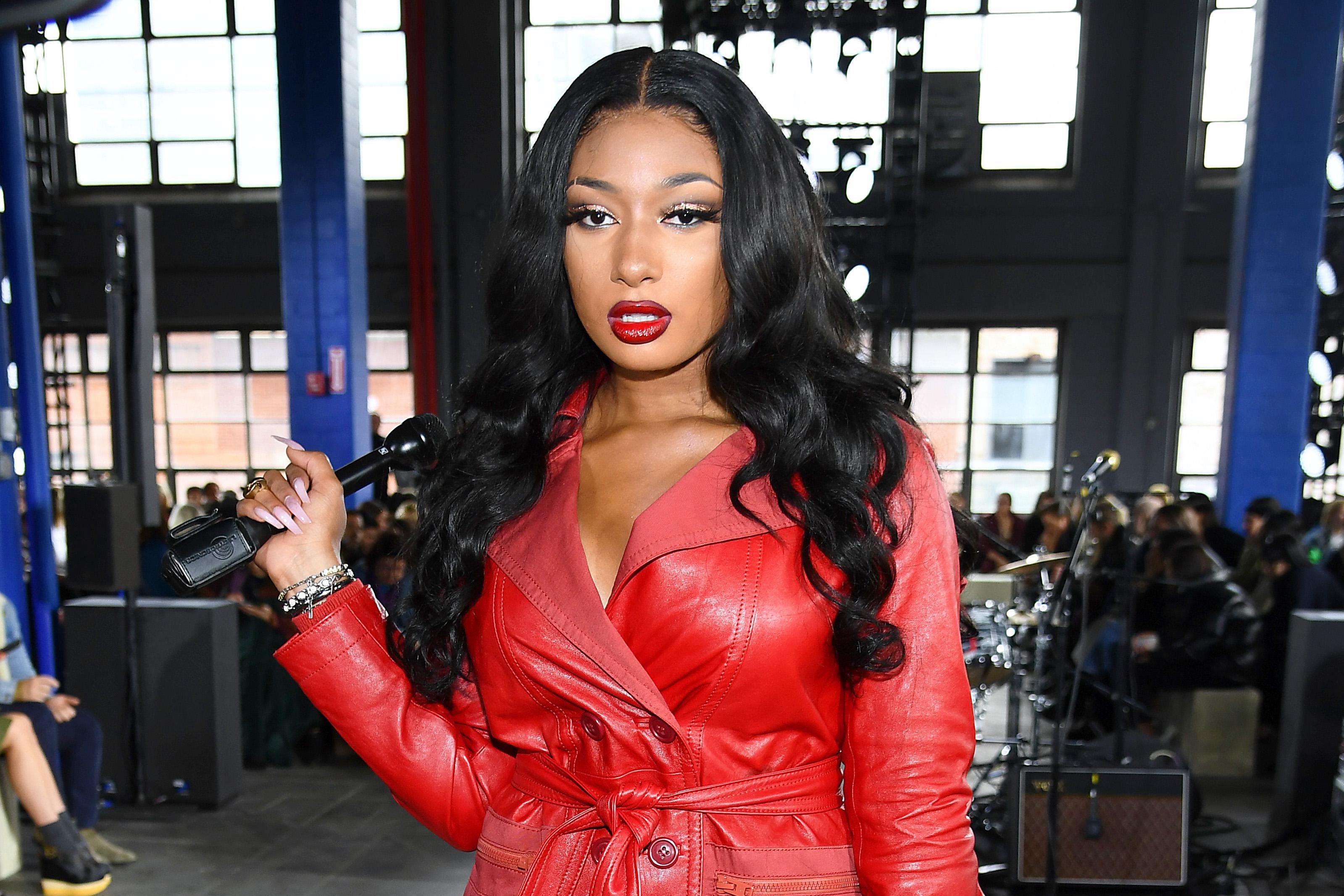 Megan Thee Stallion wears red while standing in a stadium.