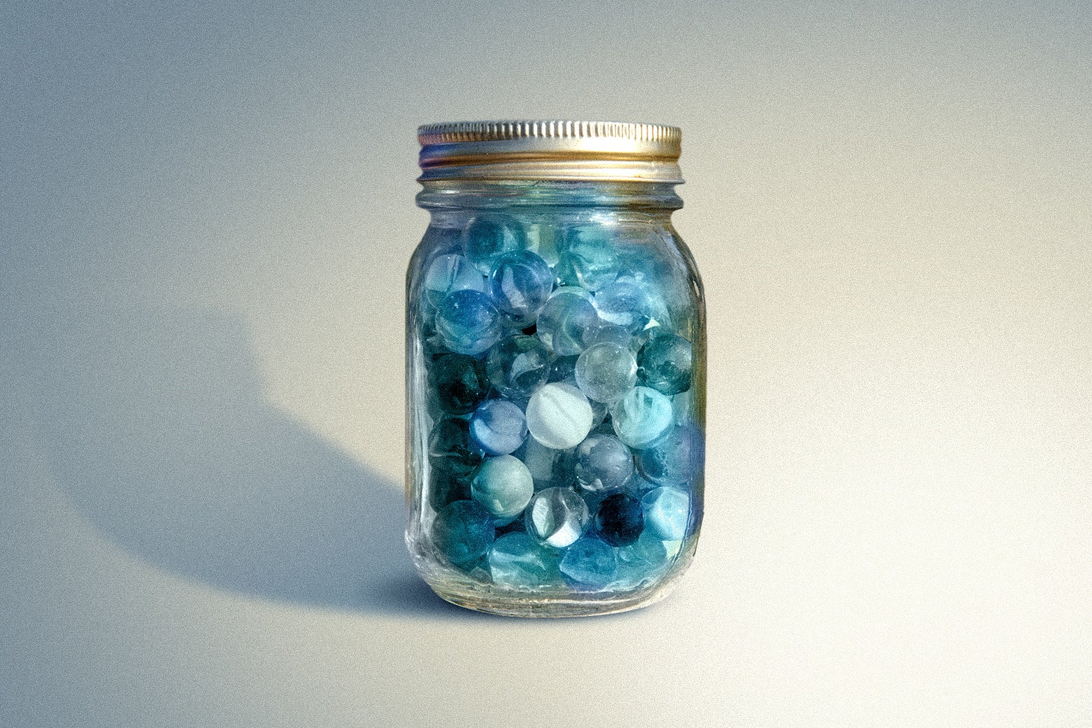 A clear mason jar full of blue marbles. 