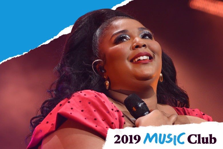 Lizzo smiling and clutching a mic to her chest.