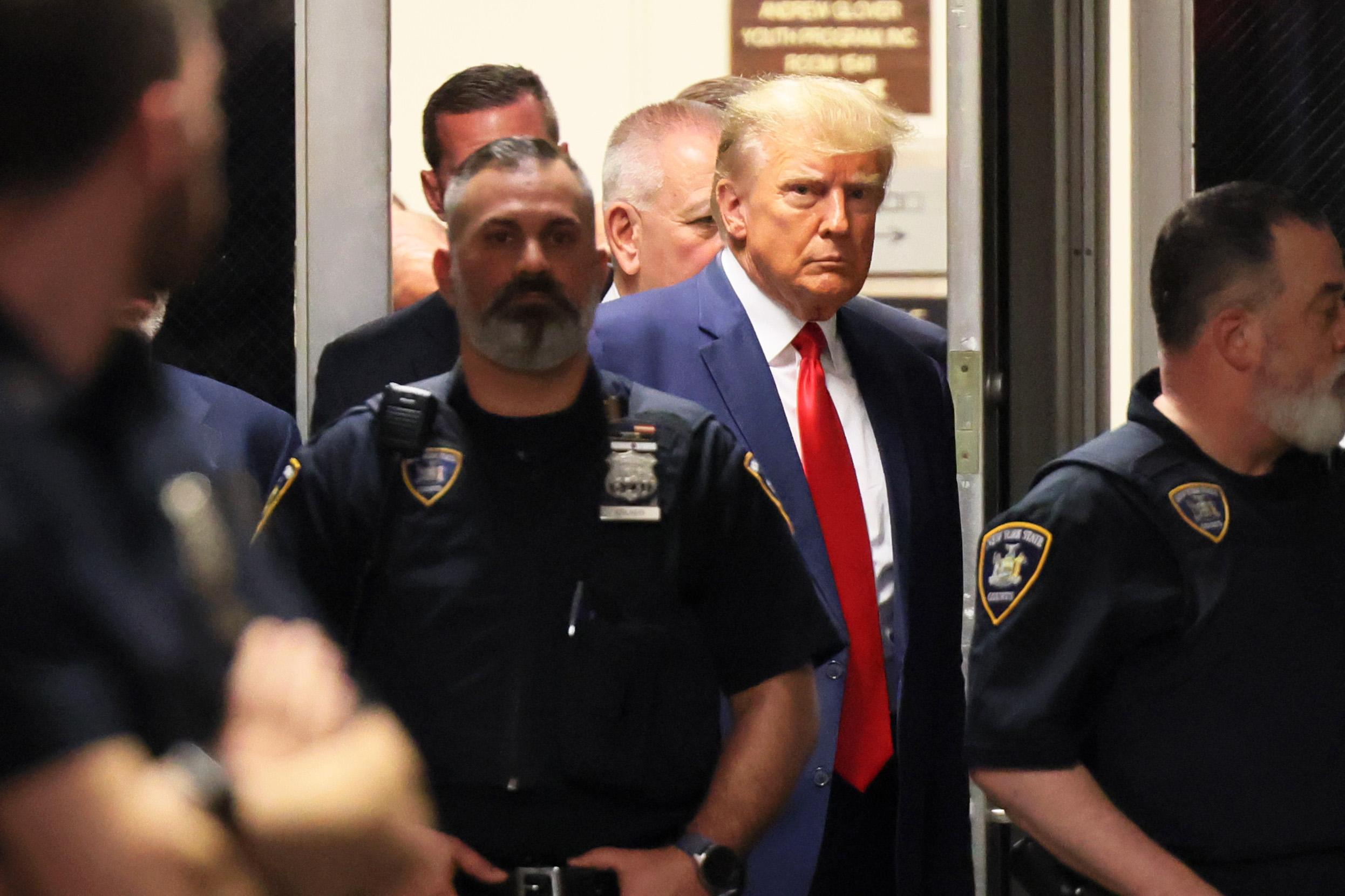 Trump glaring behind a couple of police officers.