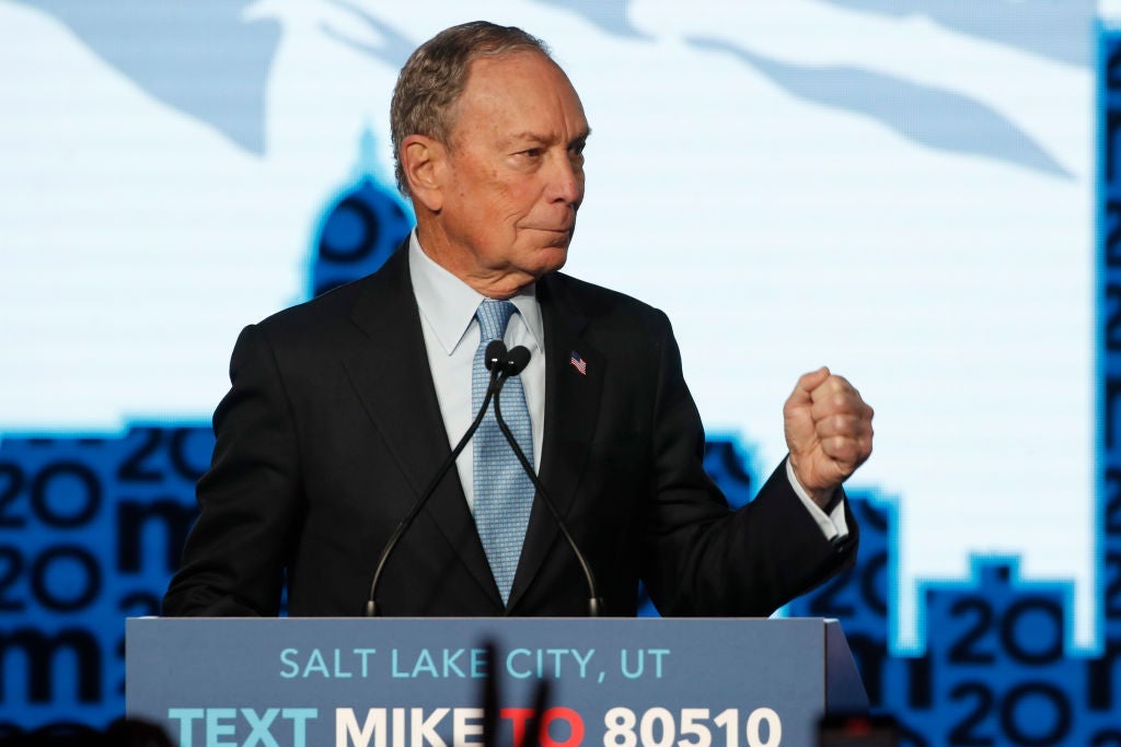 Bloomberg pumps his fist while standing at a lectern.