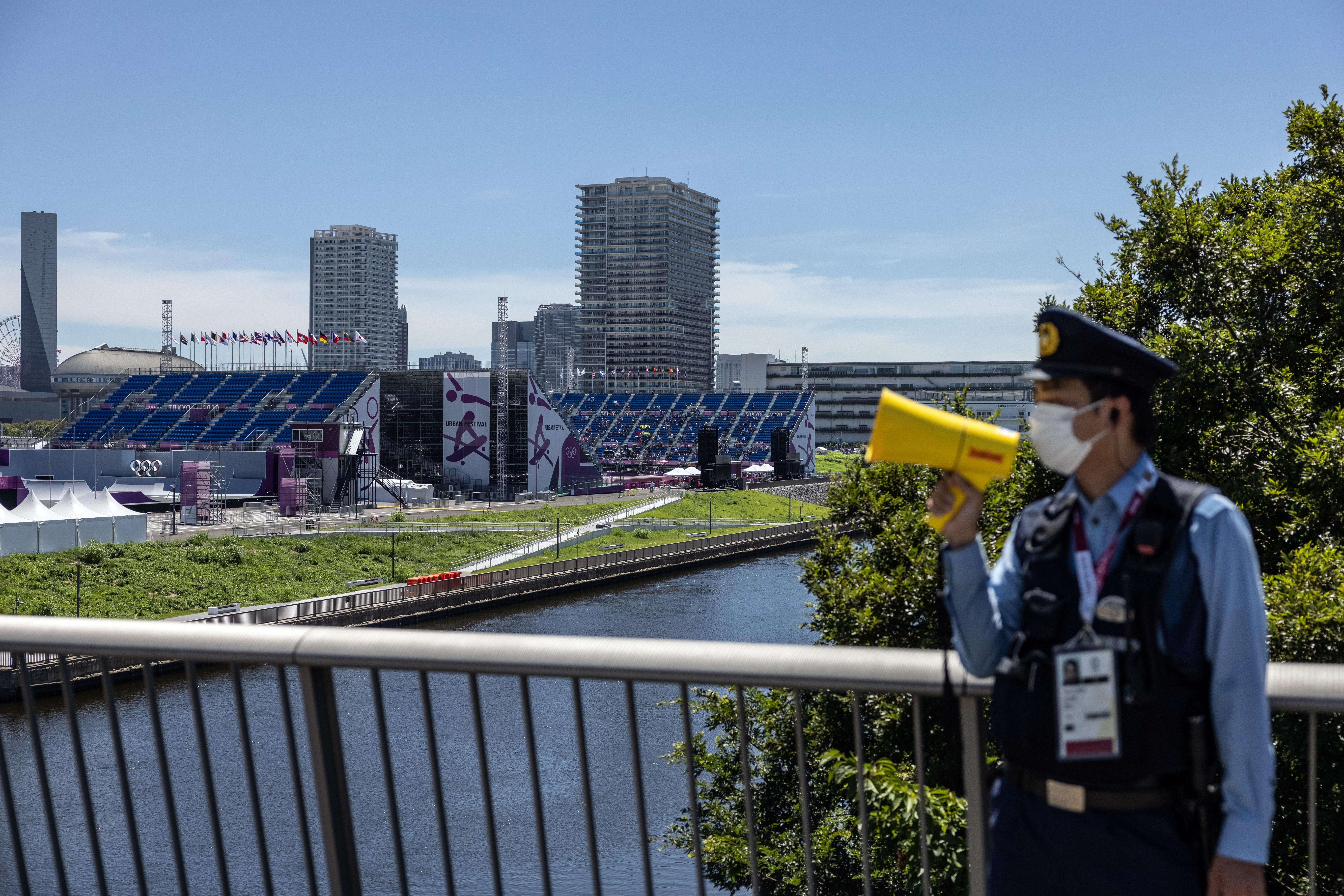 A police officer shouts into a megaphone to tell people not to gather near Ariake Urban Sports Park during the Men's Park final skateboarding competition on day 13 of the Tokyo Olympics on August 5, 2021 in Tokyo, Japan. 