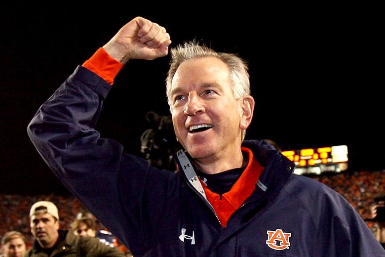 Tuberville, wearing an Auburn jacket, raises his fist in the air.