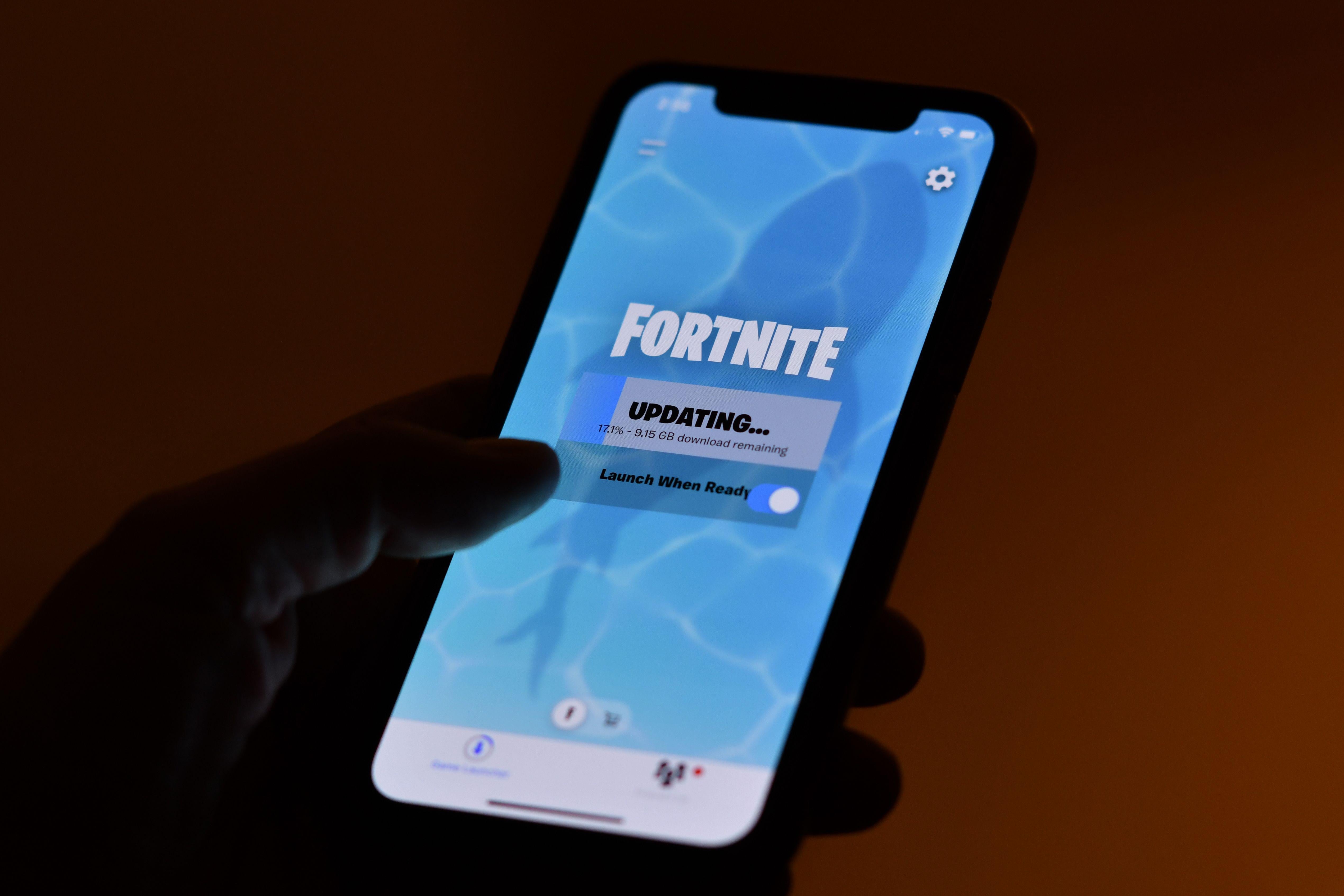 Fortnite updating on the screen of a smartphone in someone's hand