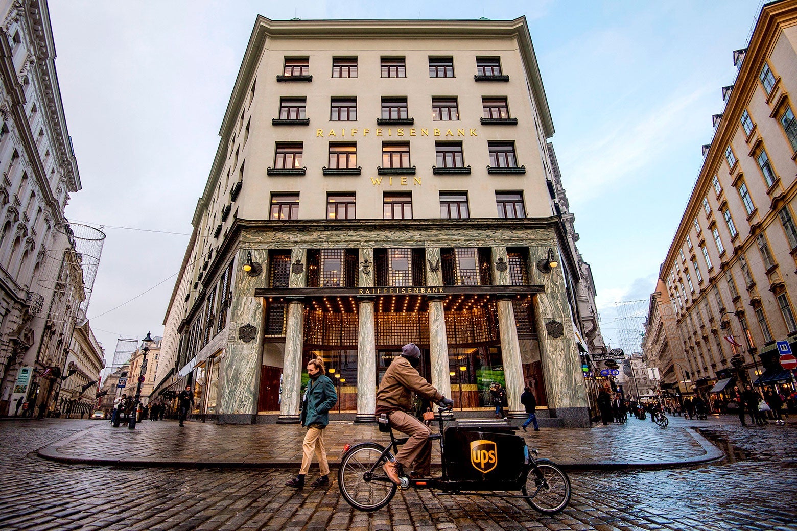 A UPS biker rides their bike in the street in front of the Looshaus.