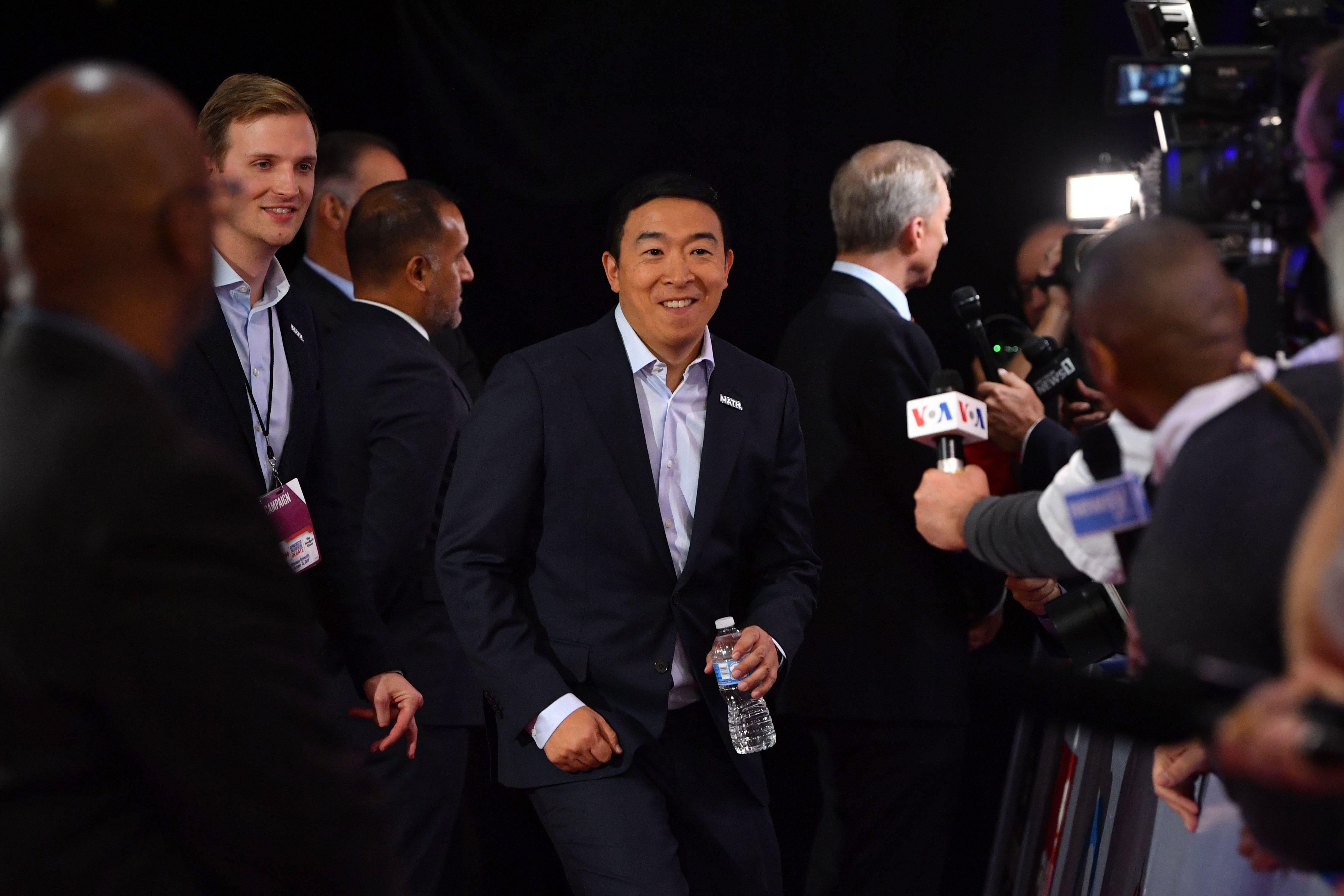 Andrew Yang enters a room full of reporters.