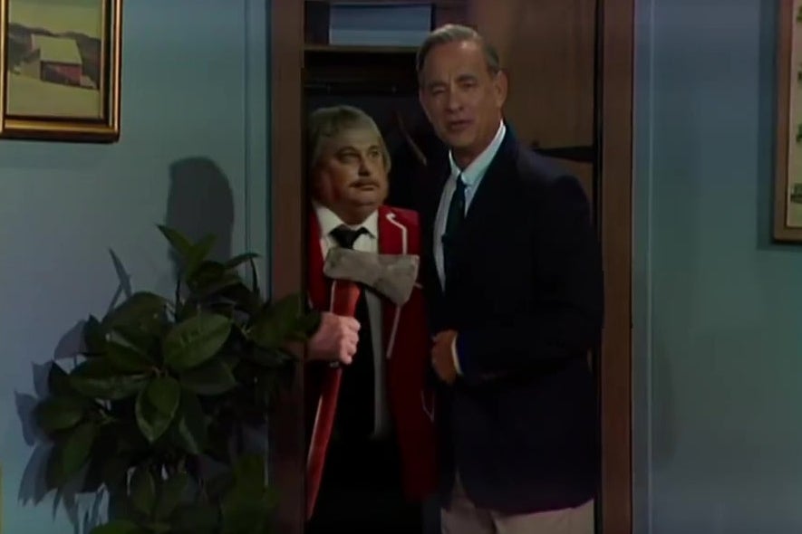 Tom Hanks, dressed as Mister Rogers, opens his closet door to find Captain Kangaroo hiding with an ax.