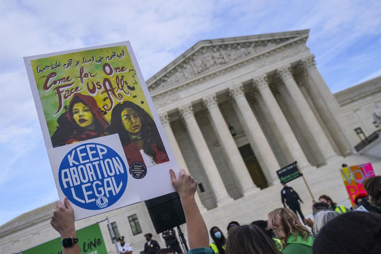 Women hold signs defending the right to abortion in front of the Supreme Court the day Dobbs was argued.
