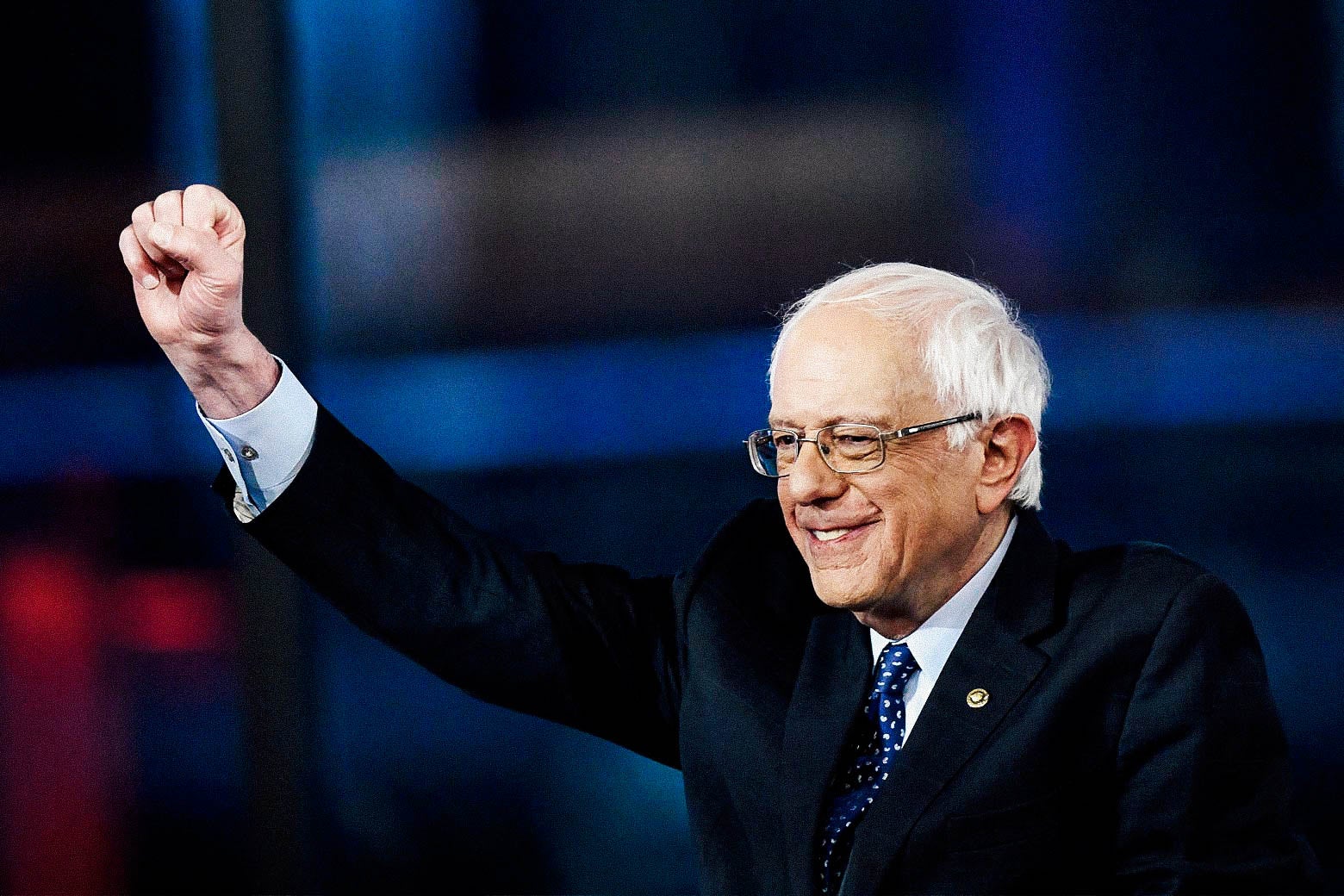 Sanders smiles and raises his fist onstage.