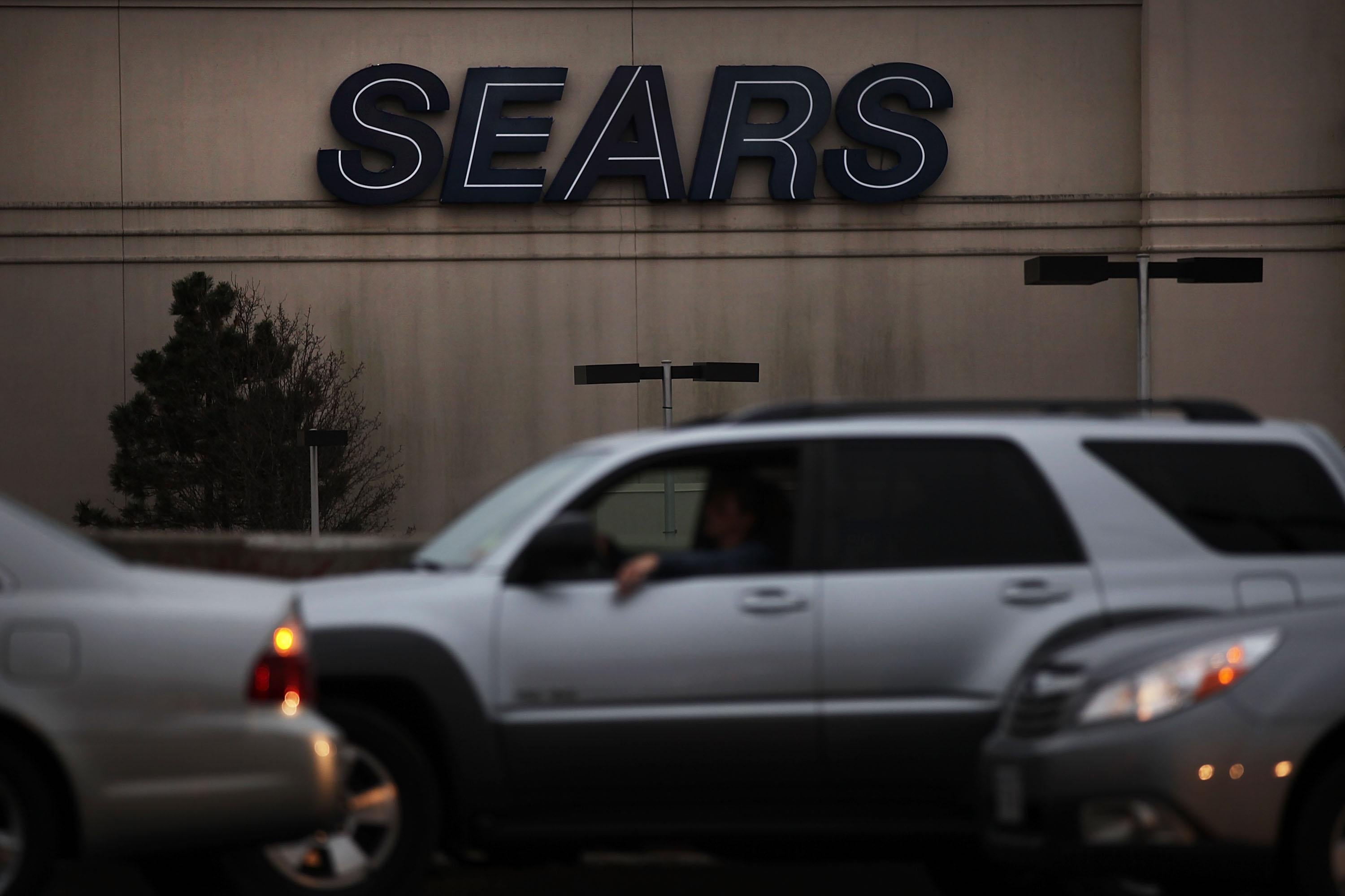 People drive by a Sears store.