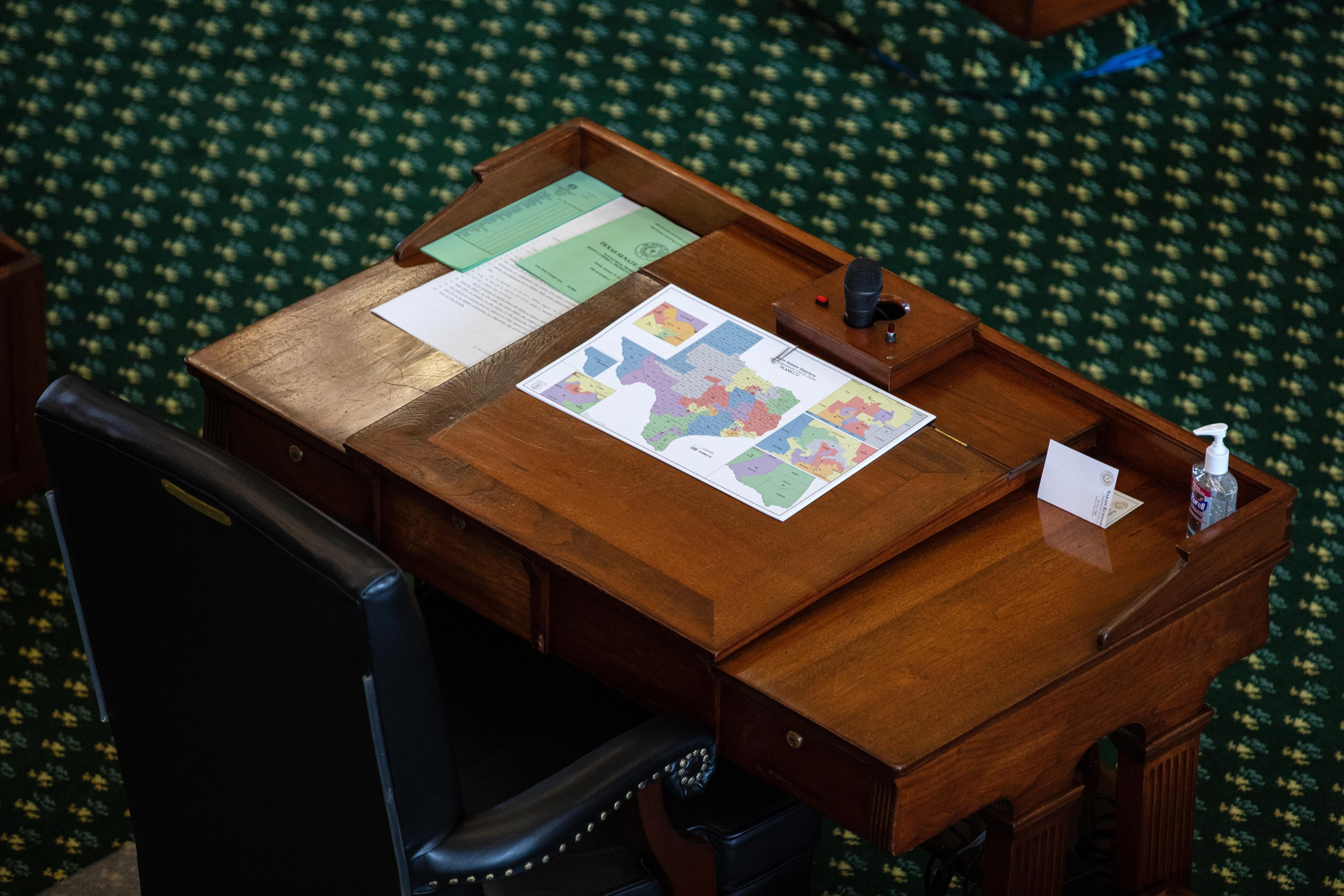 A map of Texas is seen on a desk with a chair.