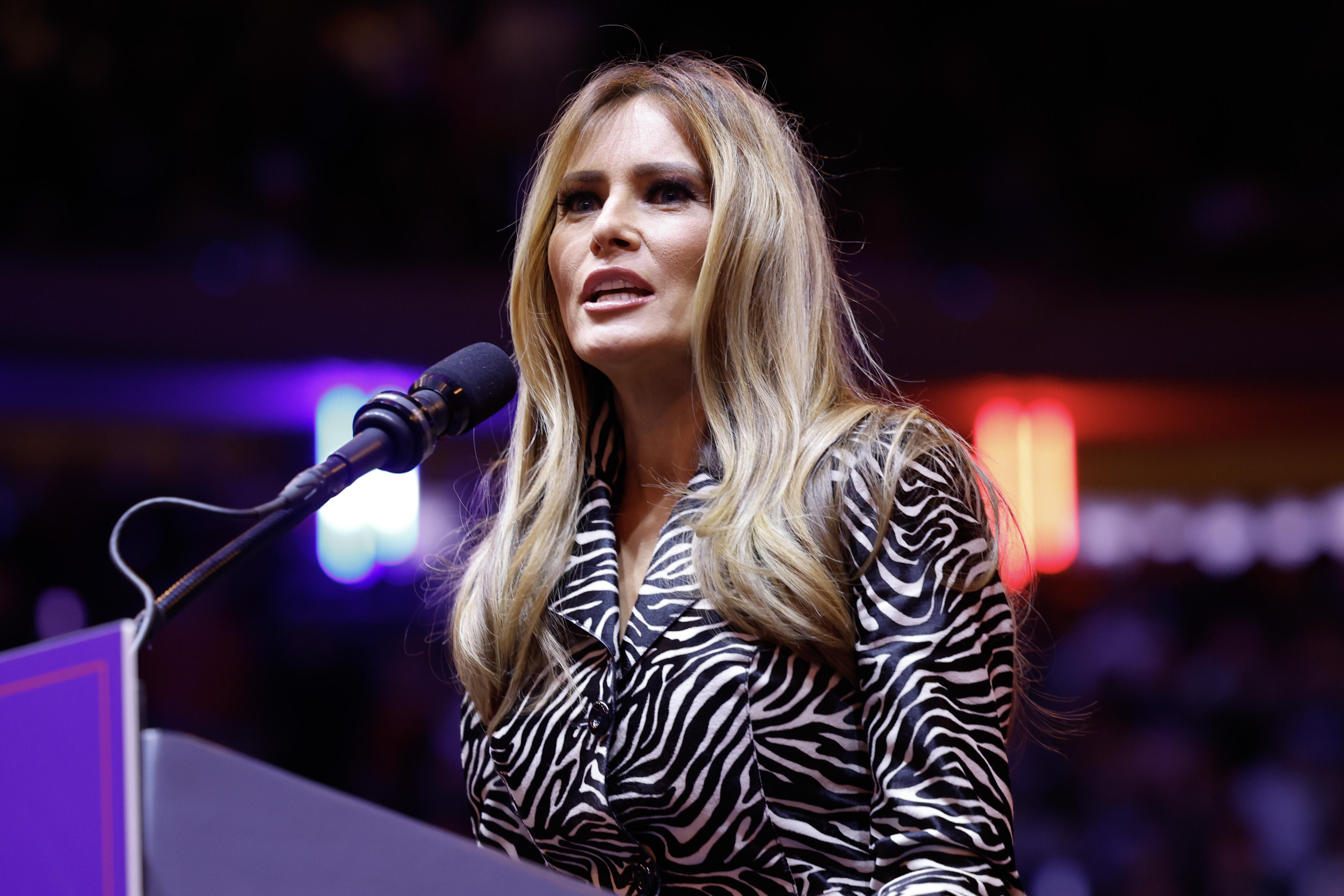 Top Stories Tamfitronics Melania wears an animal-print blazer as she stands at a podium.