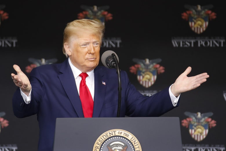 Trump raises his arms while speaking at a podium