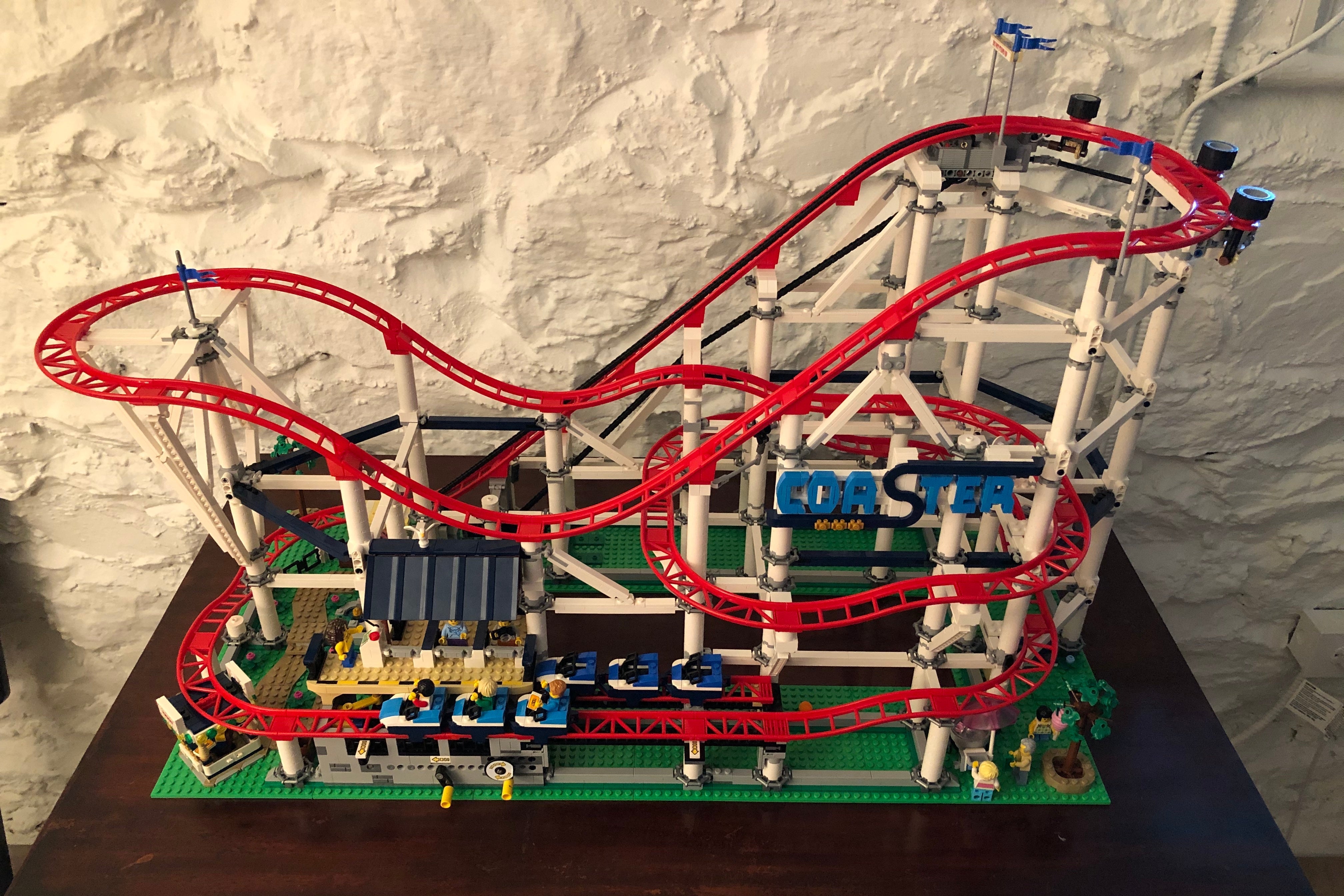 A Lego rollercoaster sitting on a table, complete with moving-looking carts and flags flying high