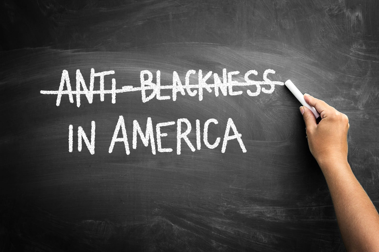 A blackboard with the text ANTI-BLACKNESS IN AMERICA written in white chalk, but "ANTI-BLACKNESS" is crossed out.