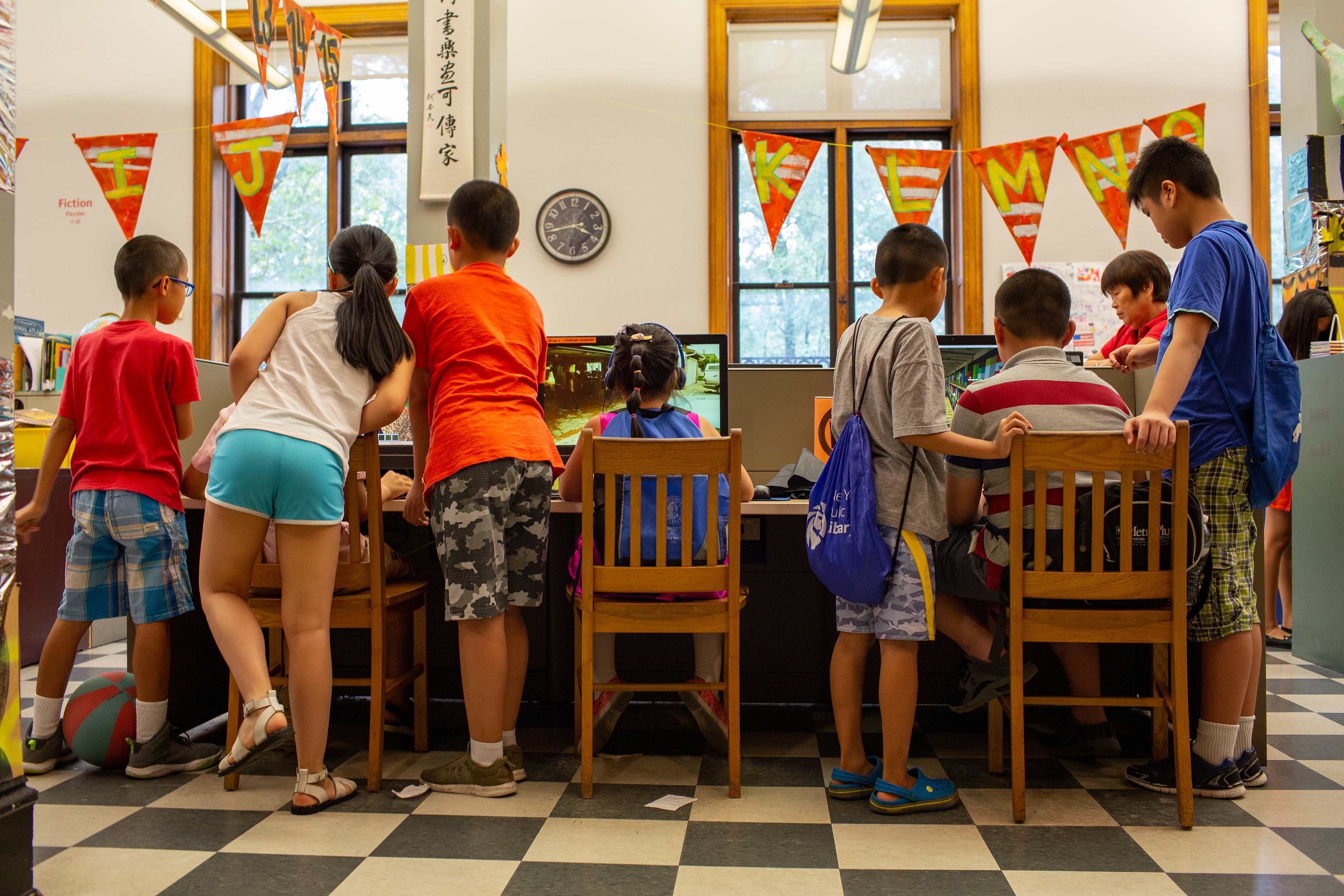 Children crowd around computers at the library.