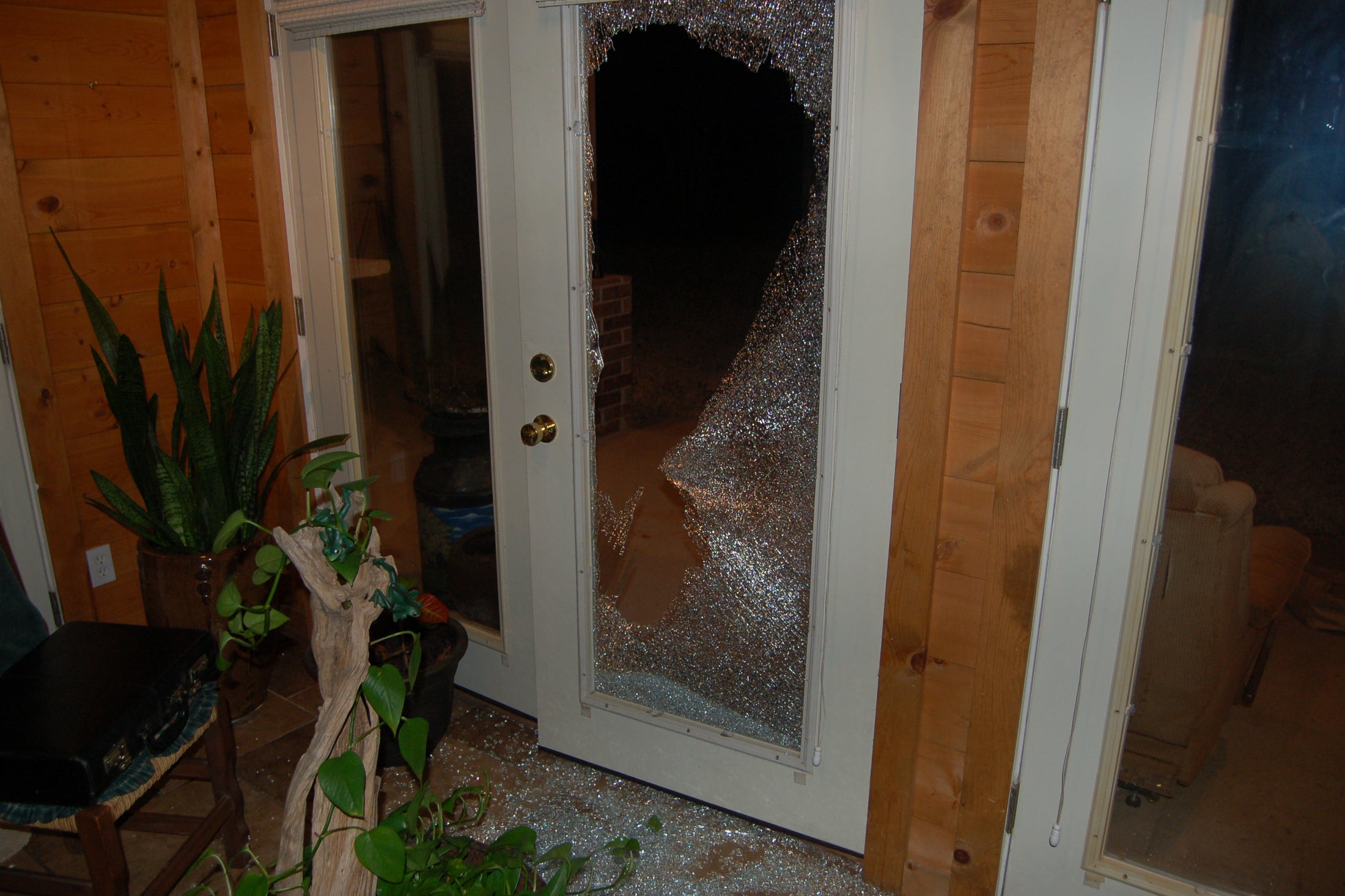 A smashed glass window in a living room.