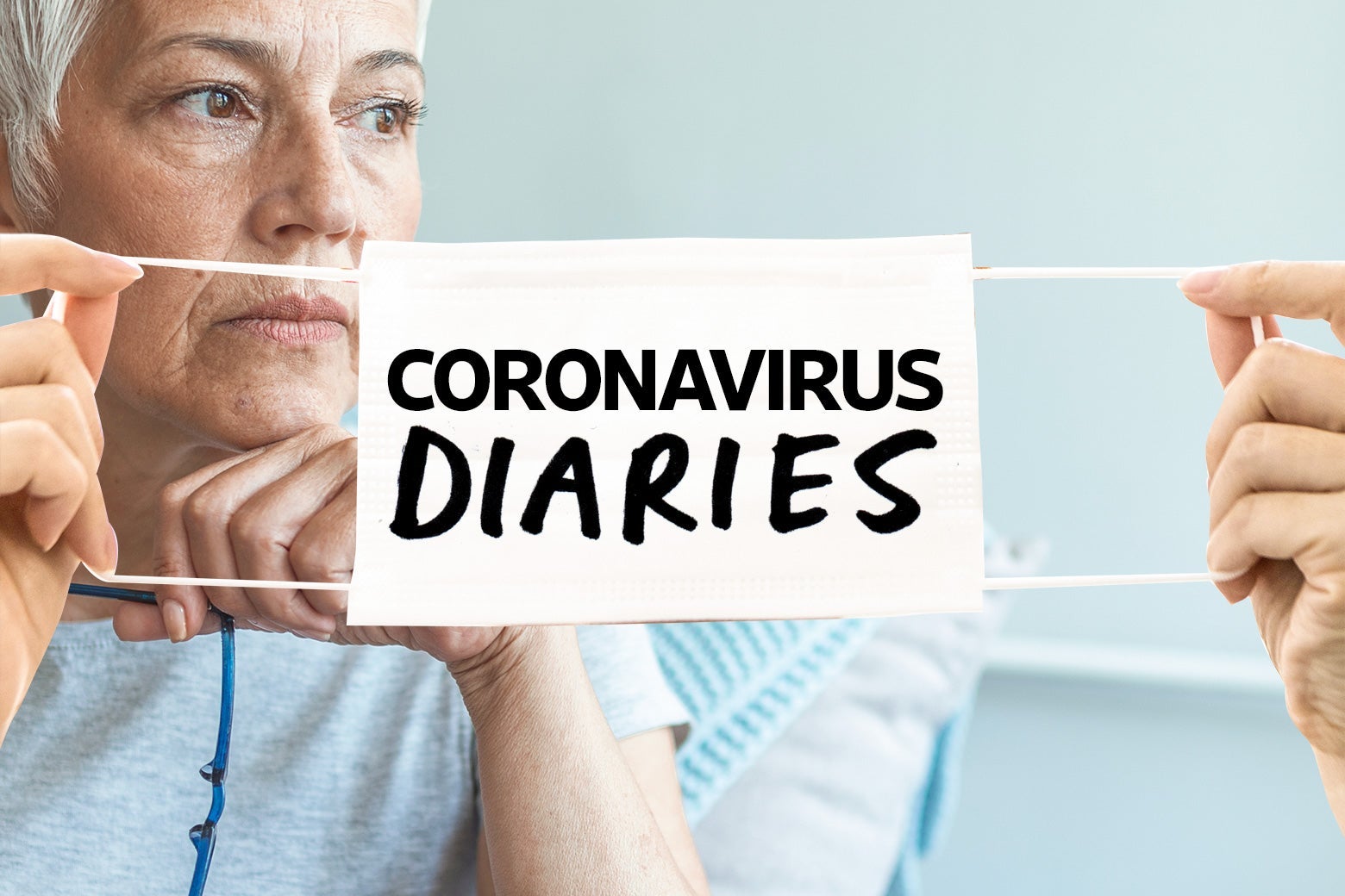 An elderly woman stares off into the distance behind two hands holding a face mask that says "Coronavirus Diaries."