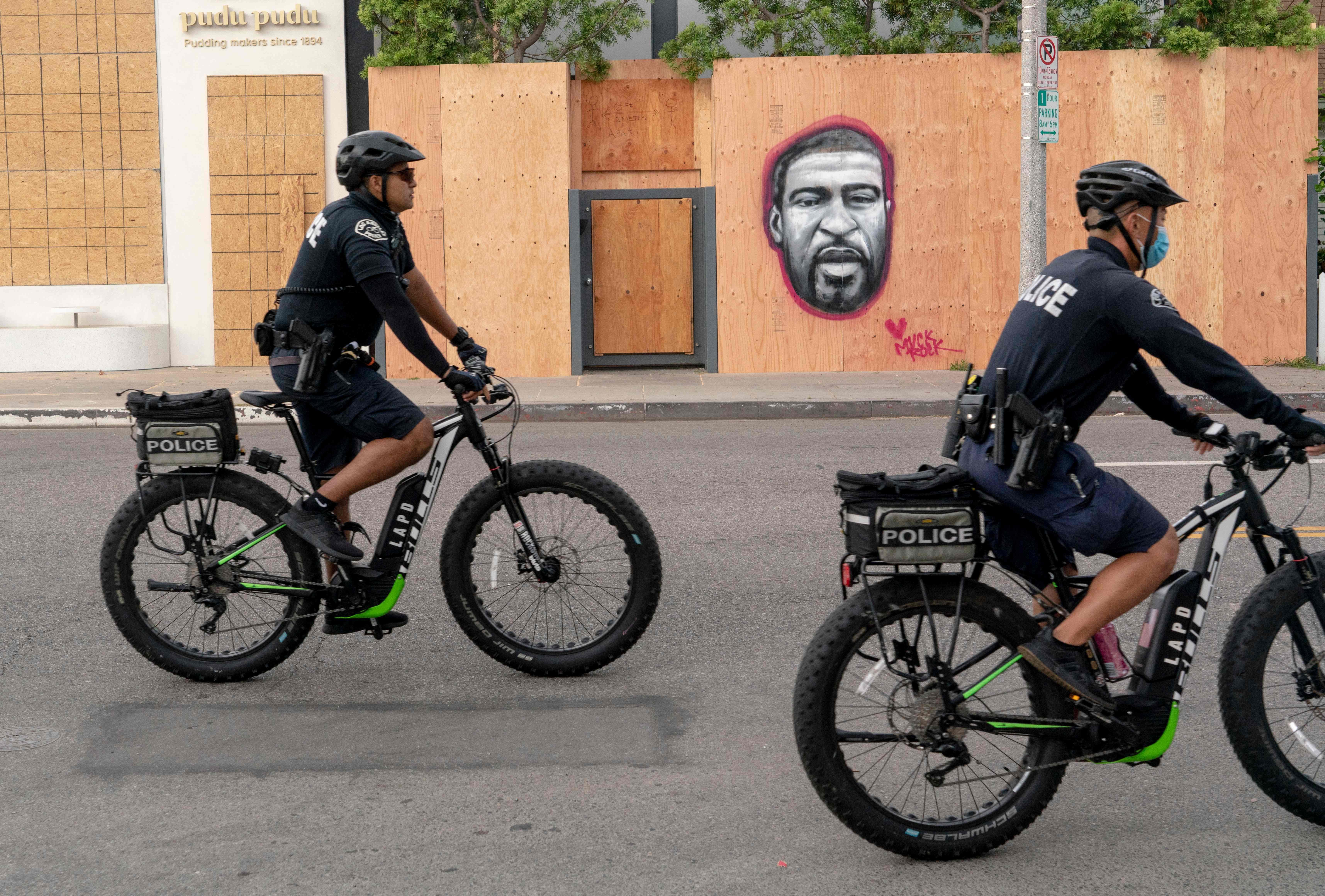 Police officers ride bicycles past a mural of George Floyd in the Venice area of Los Angeles on June 2, 2020.