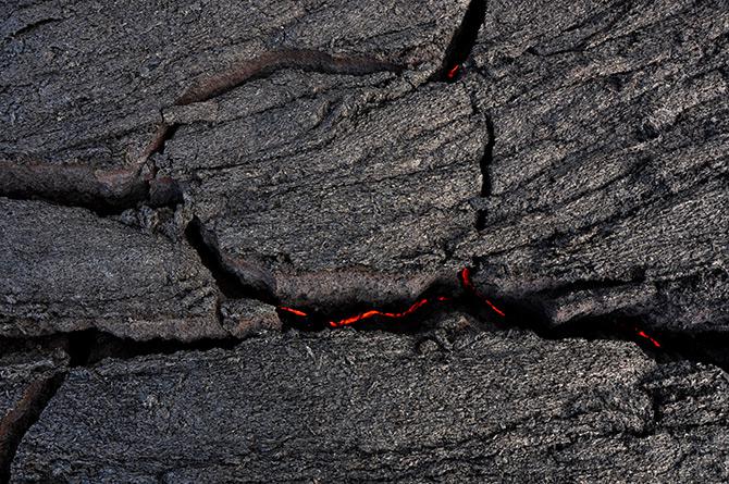 The lava flow is driven by a continual supply of molten rock just beneath the black crust, which rises and cracks as it is driven upward from below.