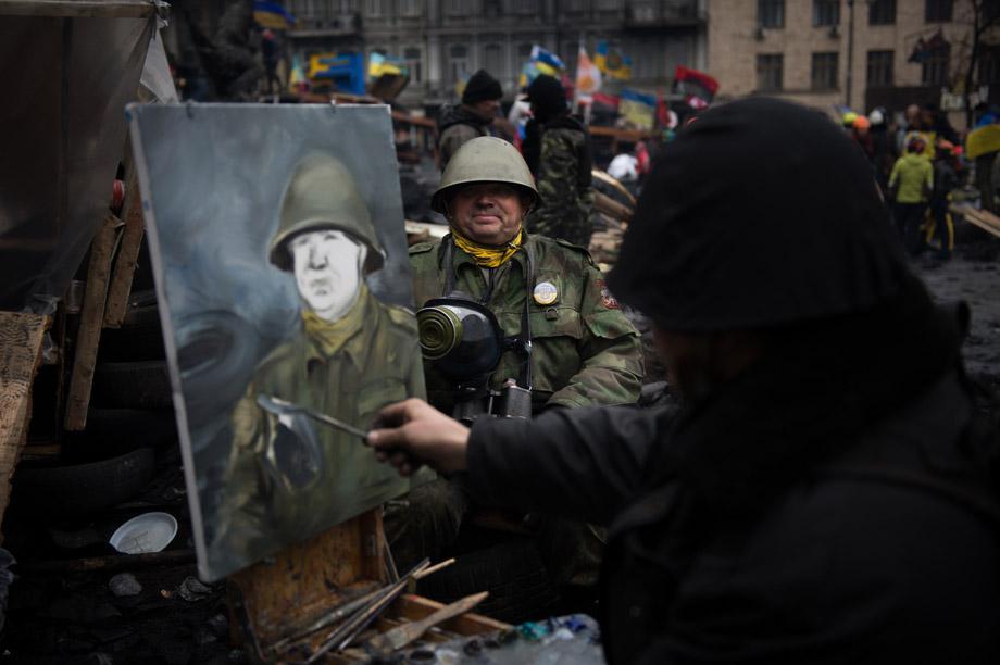 An artist paints the portrait of a protester wearing a full military outfit on a barricade in Kiev on Feb. 16, 2014. 