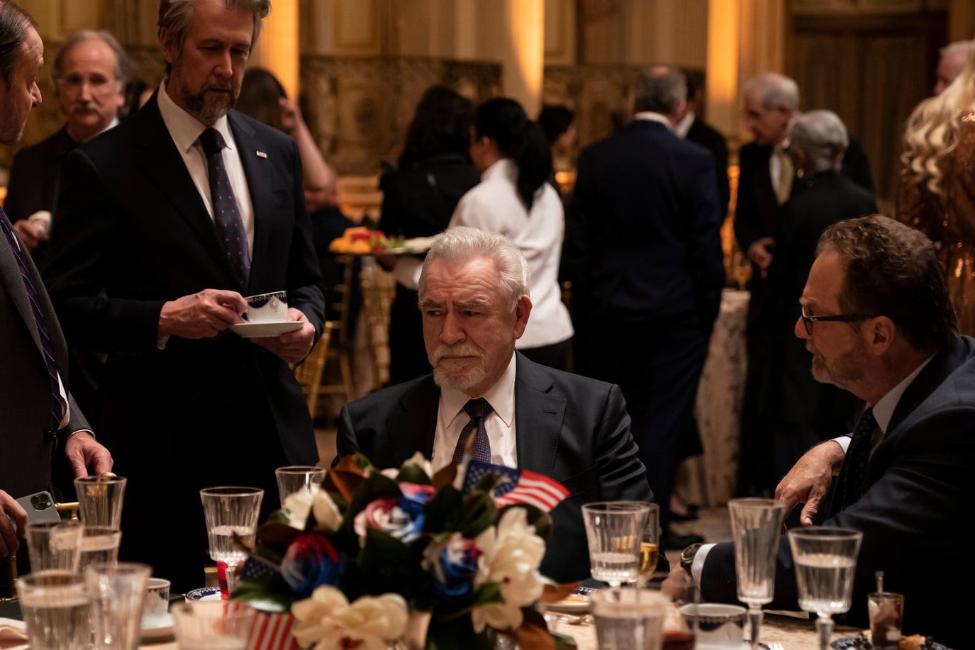 Patriarch Logan Roy at a banquet table surrounded by powerful interests.
