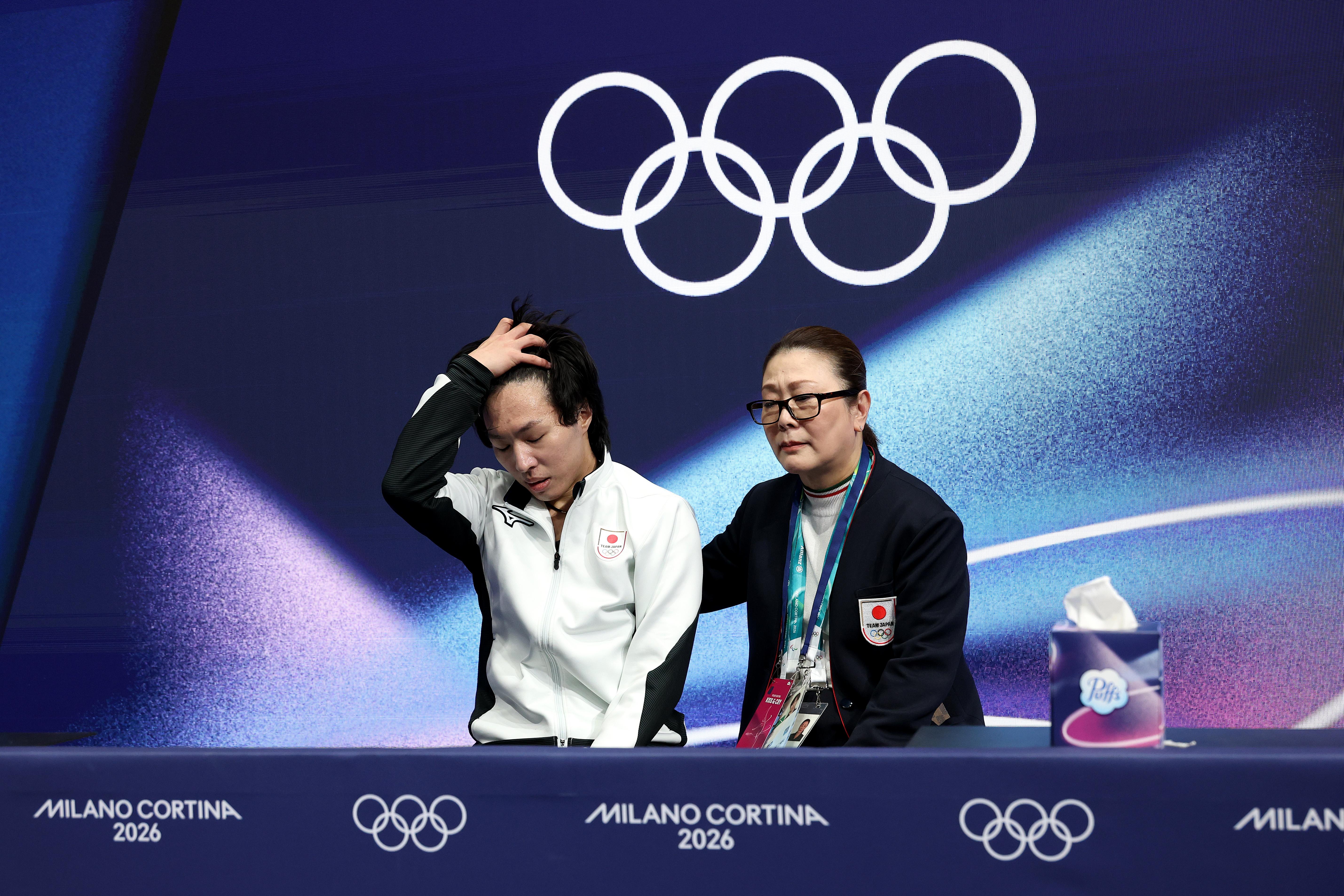 MILAN, ITALY - FEBRUARY 10: Kao Miura of Team Japan reacts with his team in the Kiss and Cry zone after competing in Men's Single Skating - Short Program on day four of the Milano Cortina 2026 Winter Olympic games at Milano Ice Skating Arena on February 10, 2026 in Milan, Italy. (Photo by Matthew Stockman/Getty Images)