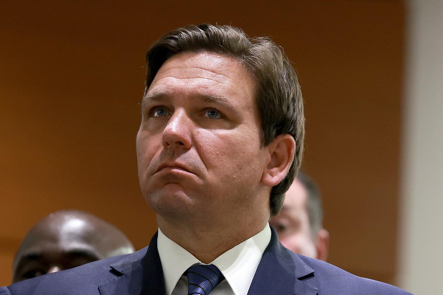 DeSantis in a suit, chin tilted up toward his right