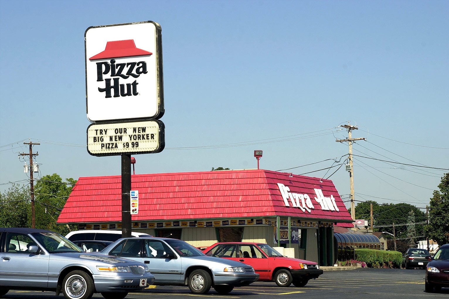 Pizza Hut as it once was, boxy, red-roofed, the sign says a pizza is $9.99.