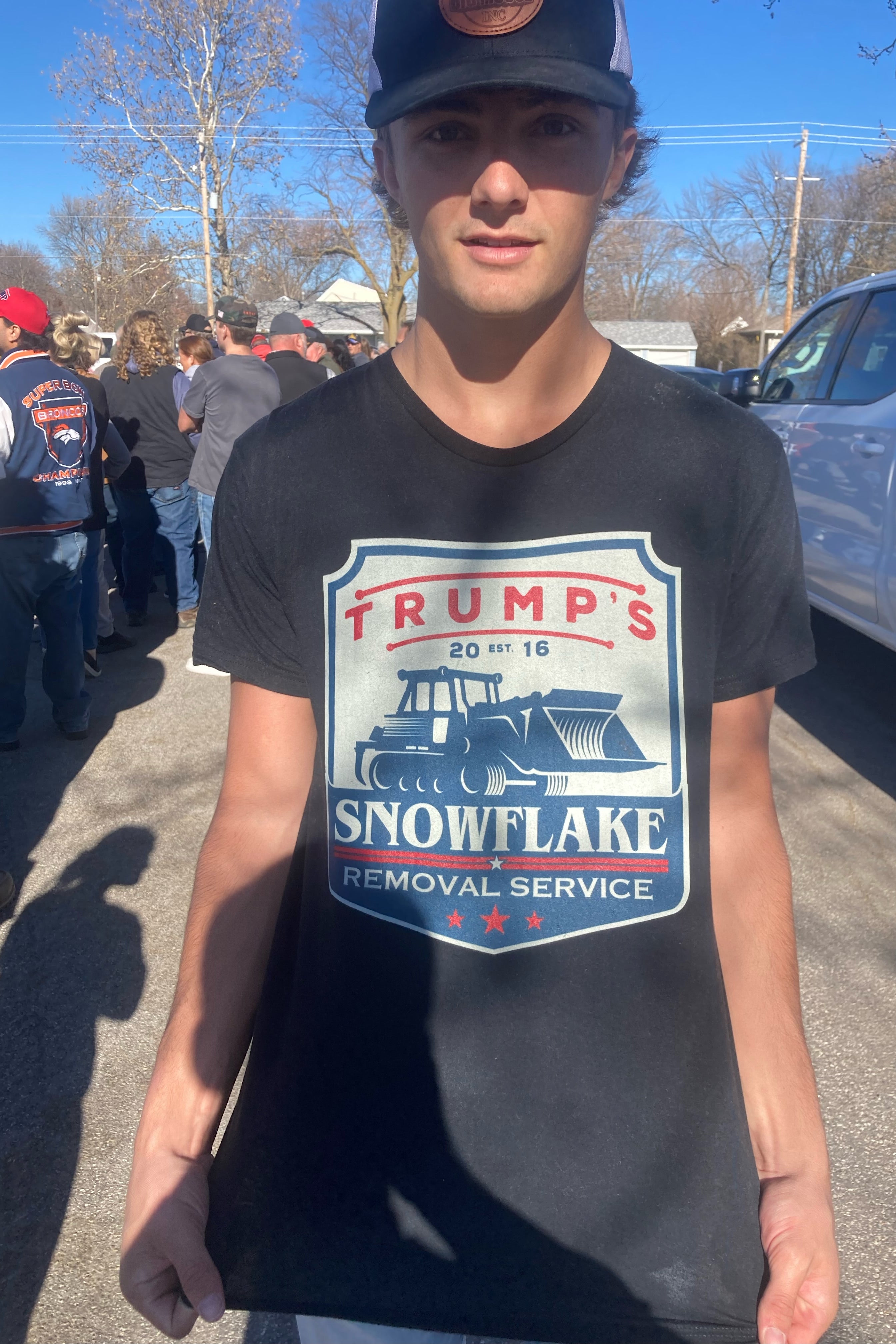 A young man wearing a shirt that says "Trump's Snowflake Removal Service, Est. 2016."