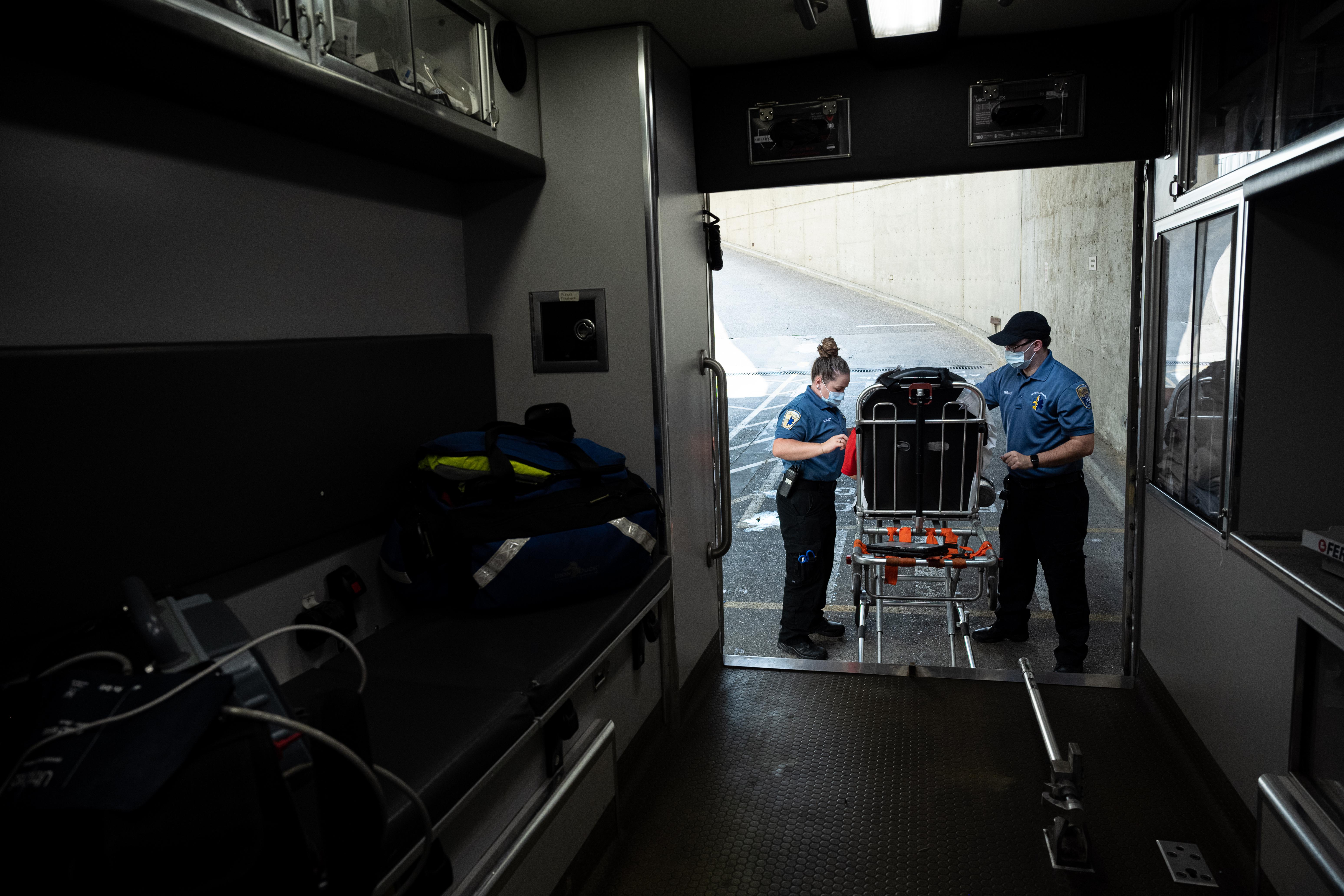 Paramedics standing beside a stretcher outside an ambulance. 