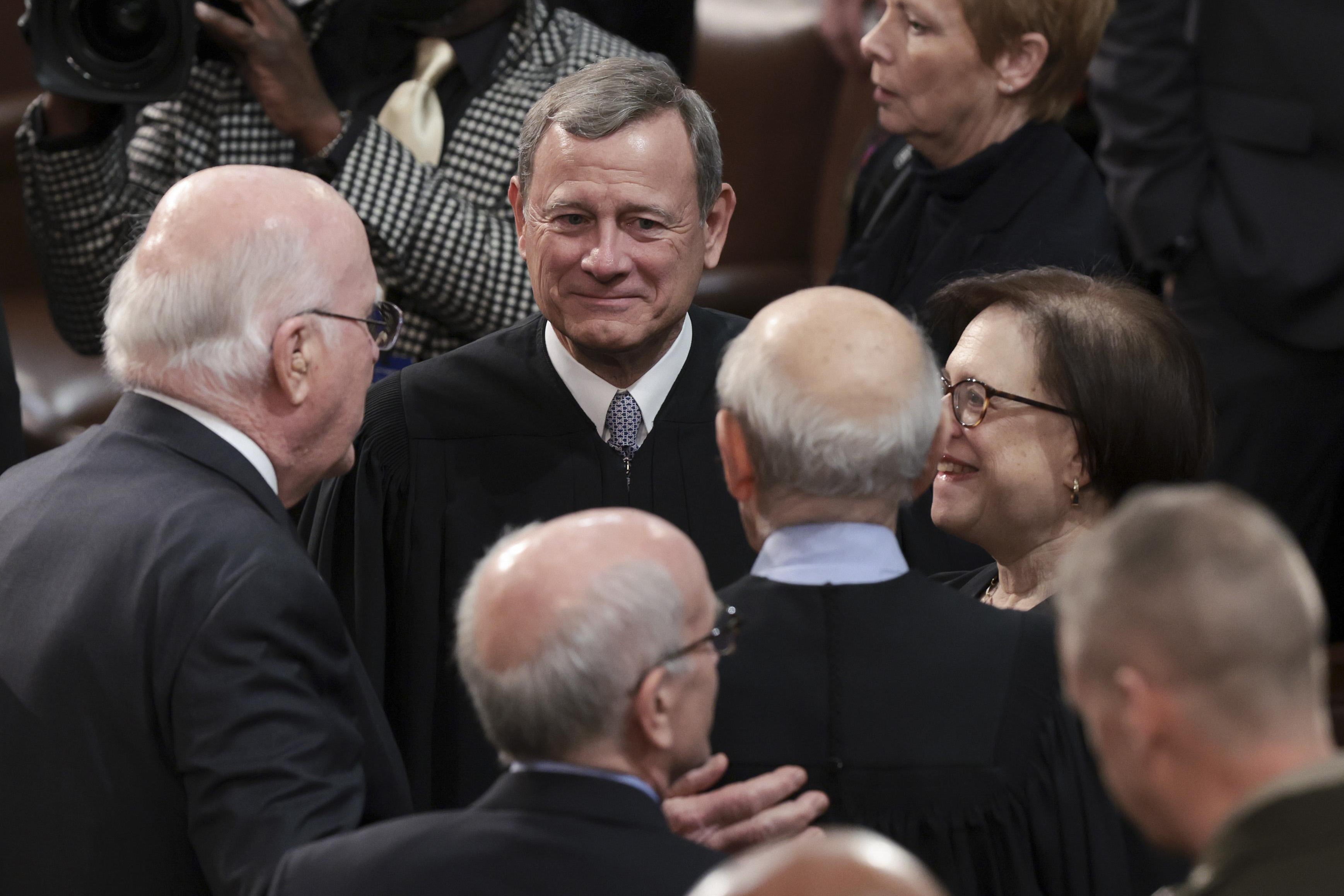 People crowd around John Roberts, in his robe, and Elena Kagan is next to him.