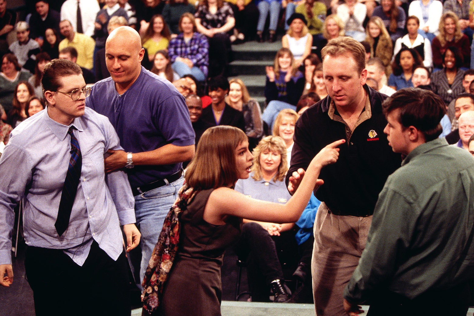 Guests argue on The Jerry Springer Show as security approaches to restrain them.