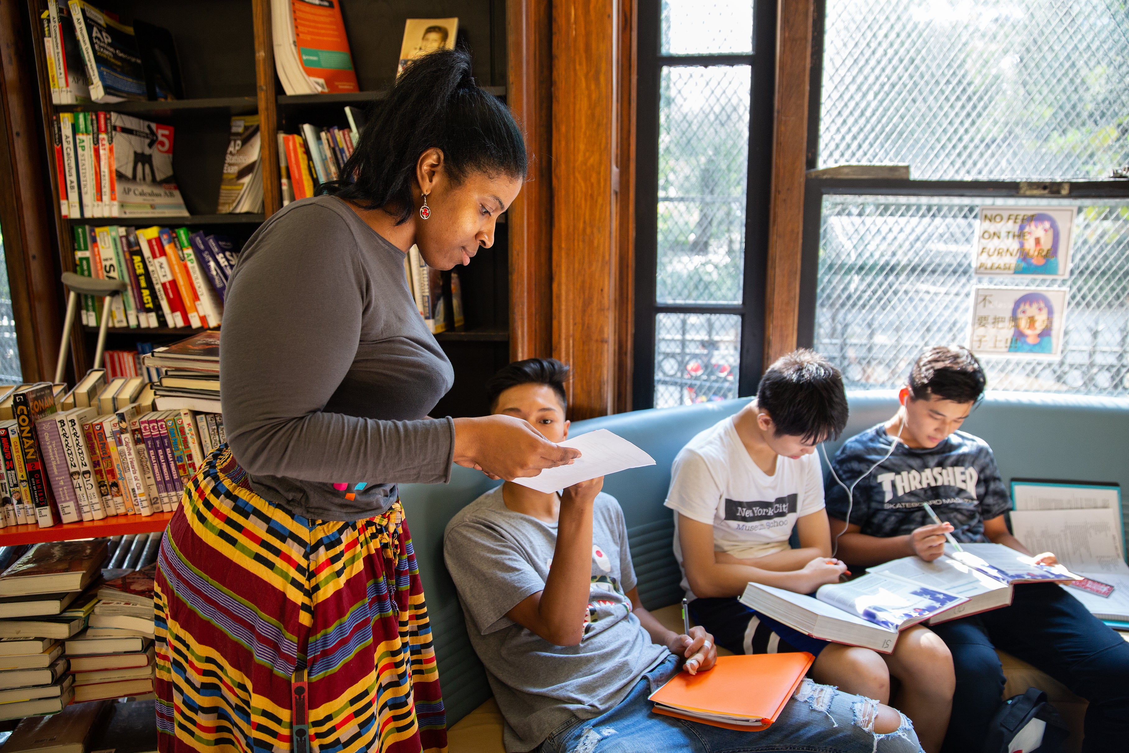 A young librarian drops by as a group of teens do their homework together.
