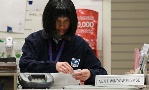 A US Postal Service worker sorts paperwork.