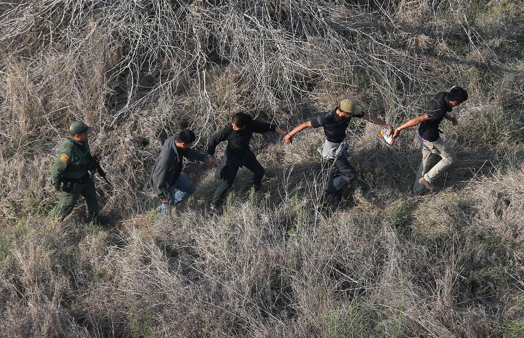 Havana, Texas A U.S. Border Patrol agent escorts a group of undocumented immigrants into custody with helicopter support from the U.S. Office of Air and Marine on May 20, 2013 near the U.S.-Mexico border in Havana, Texas. The Rio Grande Valley area has become the busiest sector for illegal immigration on the whole U.S.-Mexico border with more than a 50 percent increase in the last year. 