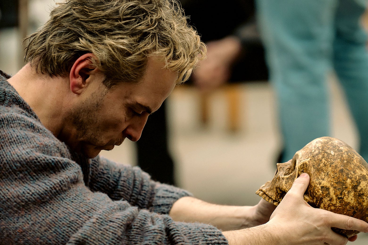 The actor, clearly not on stage, and dressed in a sweater, looks pensively down at a skull, just like in Hamlet!
