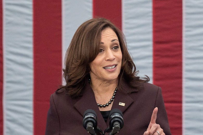 Harris pointing her left index finger up as she speaks at a podium with an American flag behind her