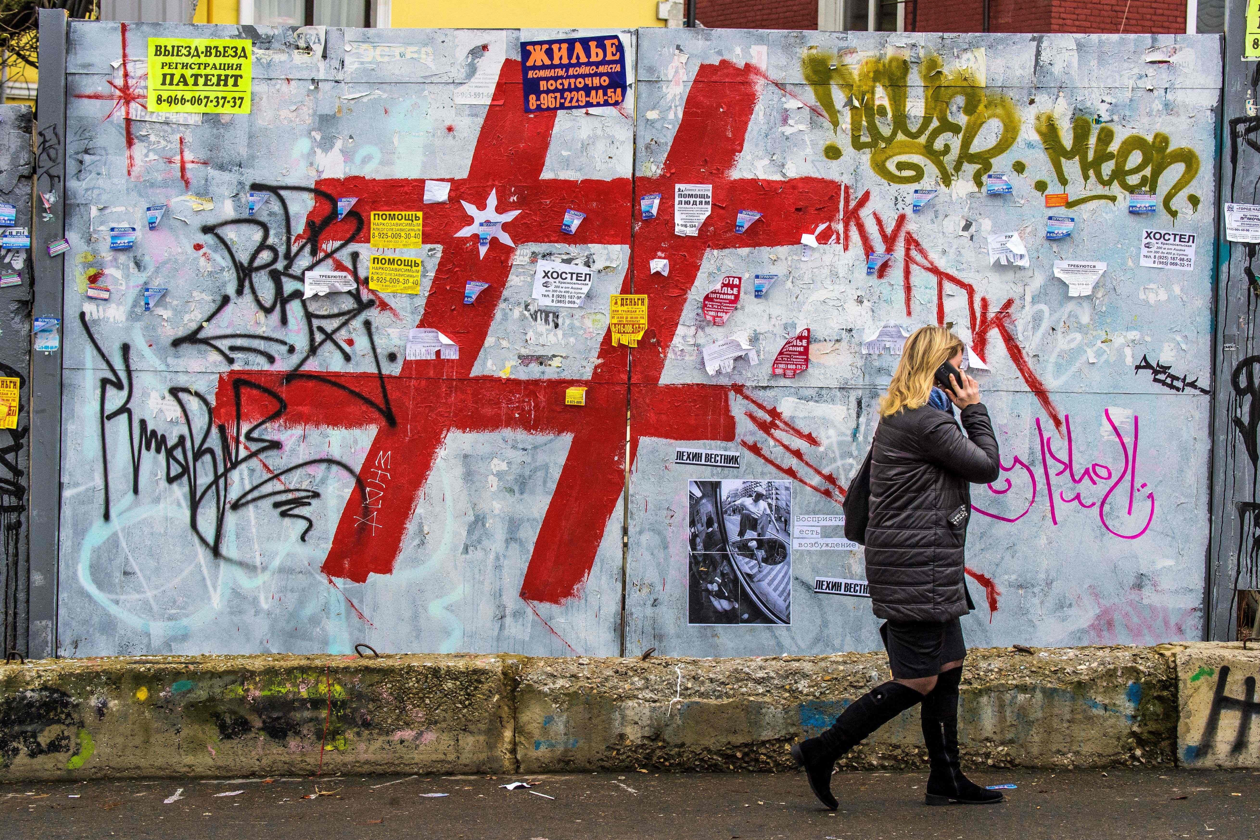 A woman speaks on a mobile phone as she walks past a graffiti covered wall with a giant hashtag sign near Moscow's Kursky railway station on November 17, 2017. / AFP PHOTO / Mladen ANTONOV        (Photo credit should read MLADEN ANTONOV/AFP/Getty Images)