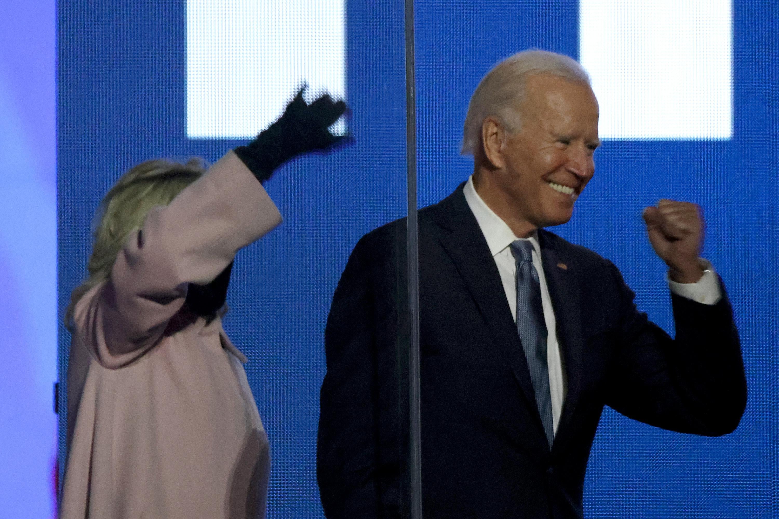 Joe Biden grins and pumps his fist next to his wife, Jill, who waves to the crowd.
