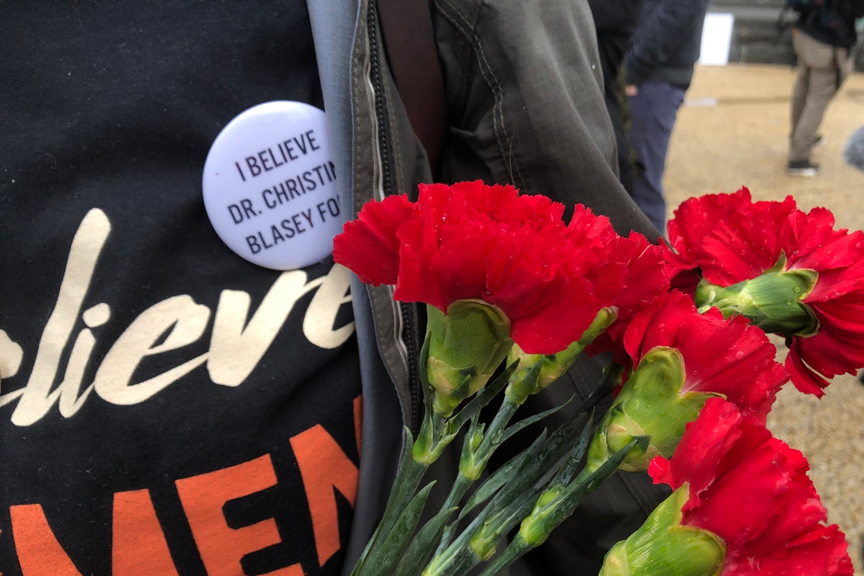 Protester Laura O'Grady holding red flowers in support of Christine Blasey Ford. (Jennifer Kang/Slate)